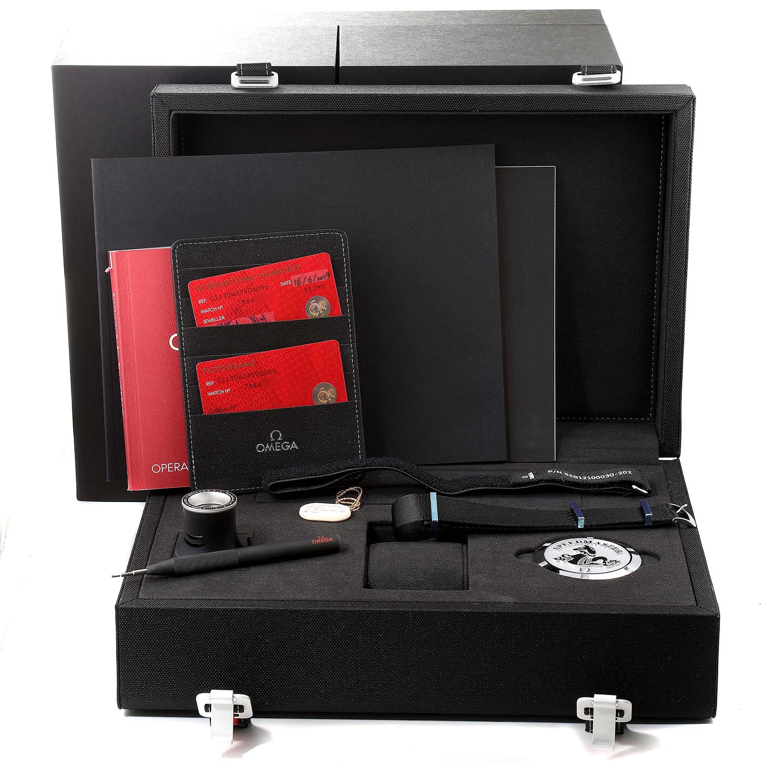 The image shows accessories for the Omega Speedmaster 311.30.42.30.01.006 Men's Stainless Steel Black Dial 311.30.42.30.01.006 Men's Stainless Steel Black Dial, including documentation, tools, a strap, a badge, and a loupe, within a black case.