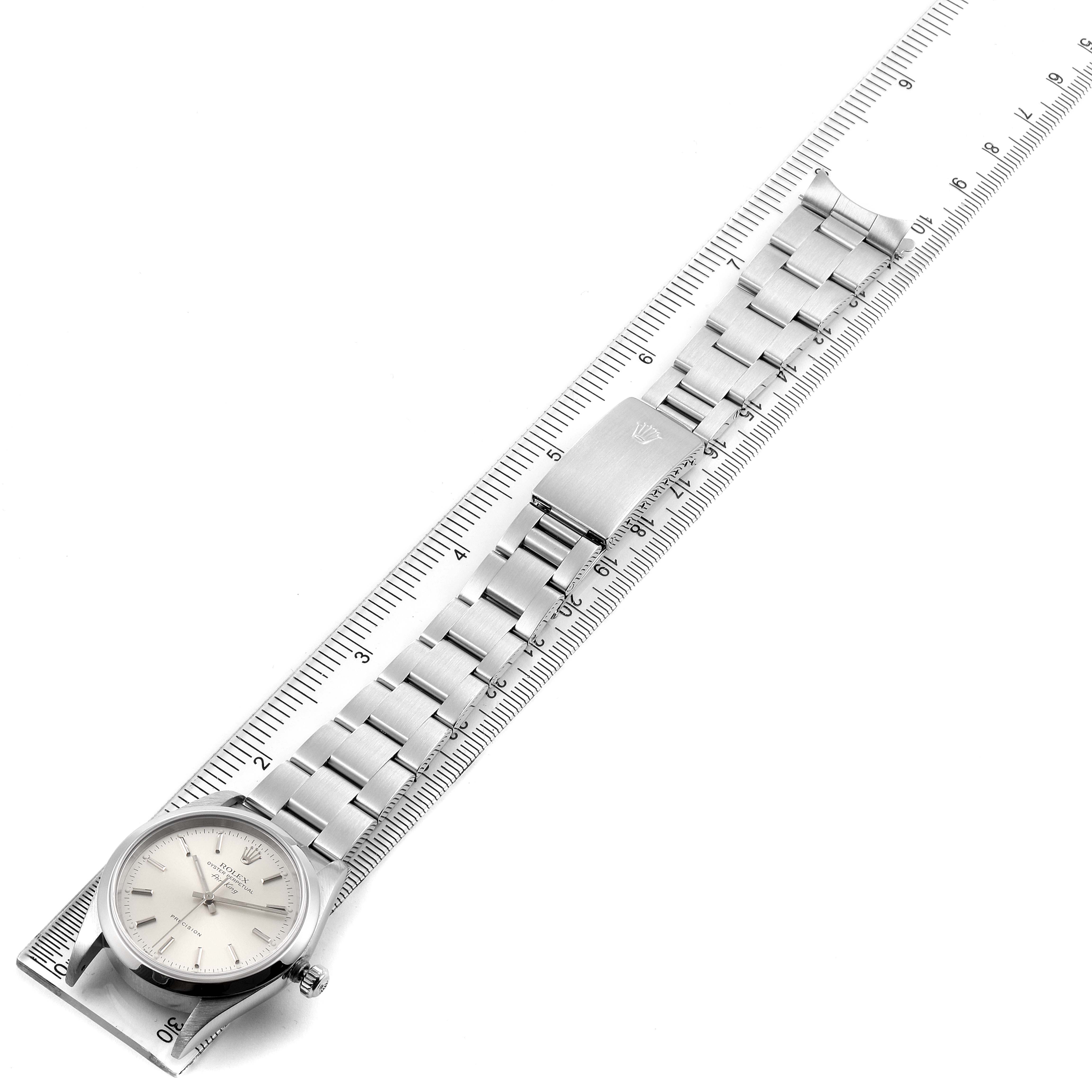 The Rolex Air-King 14000 Men's Stainless Steel Silver Dial 14000 Men's Stainless Steel Silver Dial watch is shown laid flat alongside a ruler, displaying its face, bracelet, and clasp.