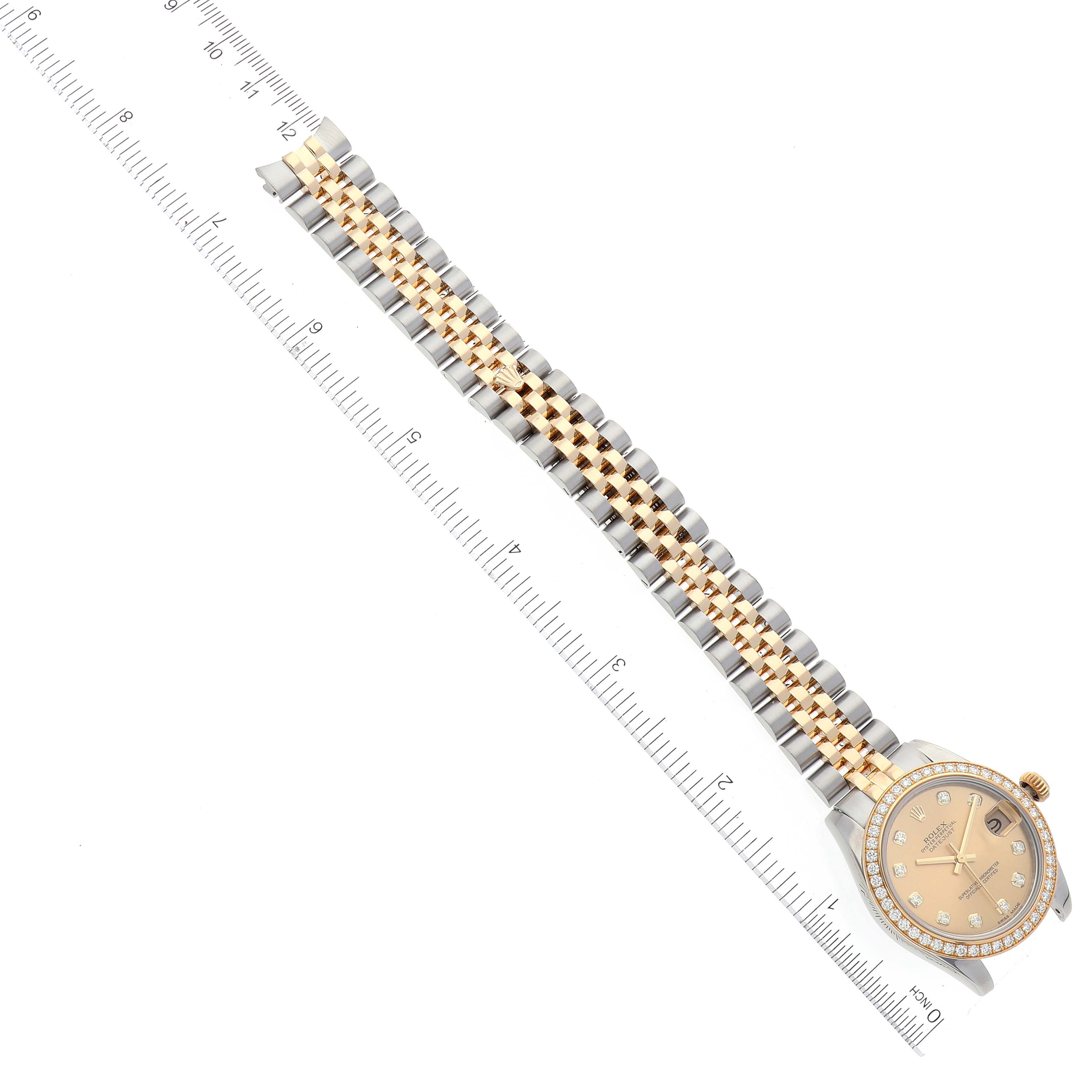 The image shows a top-down view of a Rolex Mid-Size 178383 Women
s Steel and Gold (two tone) Champagne Dial 178383 Women
s Steel and Gold (two tone) Champagne Dial model watch with a gold and silver bracelet next to a measuring ruler.