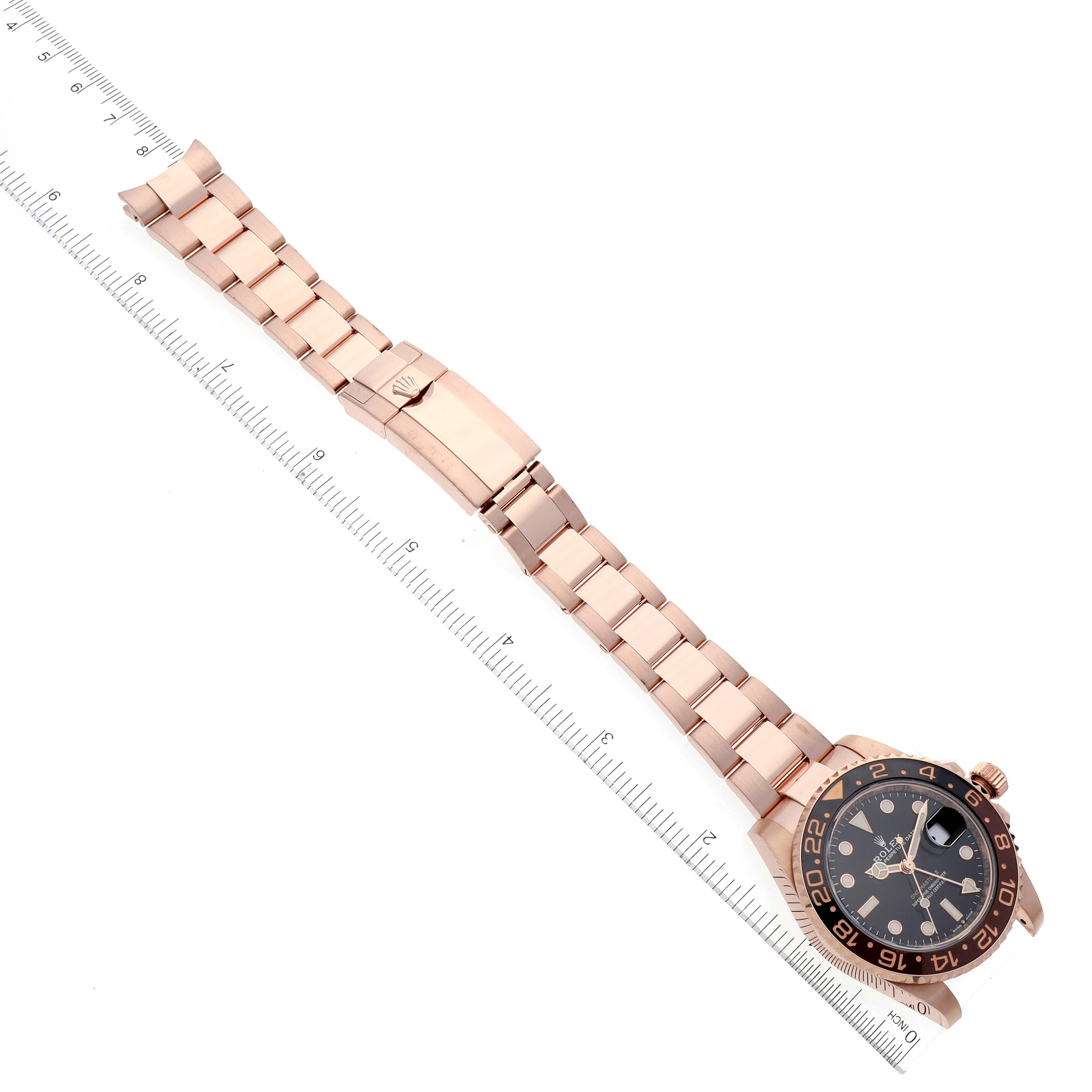 This image shows a Rolex GMT-Master 126715 Men
s Rose Gold Black Dial 126715 Men
s Rose Gold Black Dial watch horizontally laid out with the face, bezel, and bracelet visible alongside a ruler.
