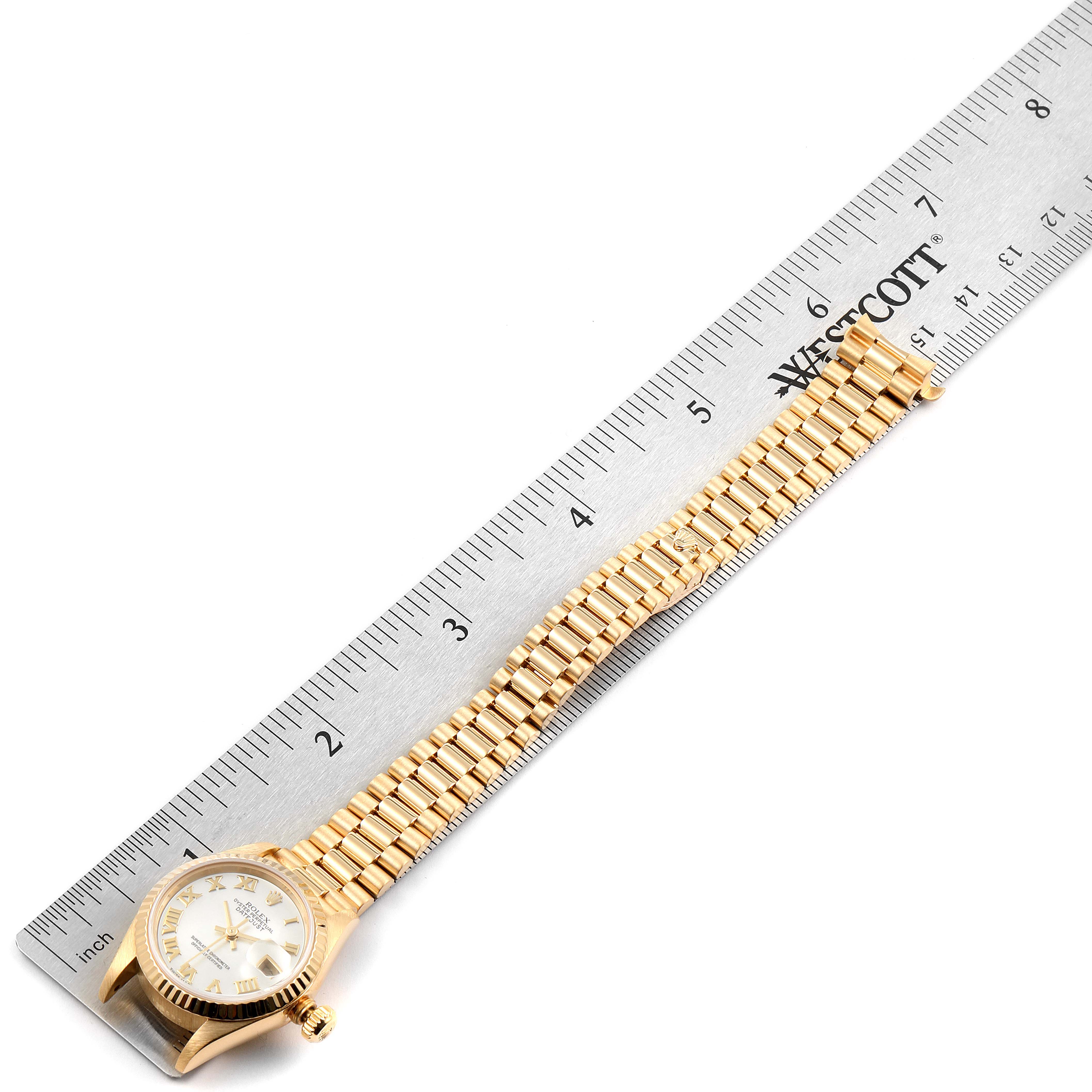 The image shows a Rolex President 79178 Women
s Yellow Gold Mother of Pearl Dial 79178 Women
s Yellow Gold Mother of Pearl Dial model watch laid flat, with its gold bracelet fully extended next to a ruler for scale.