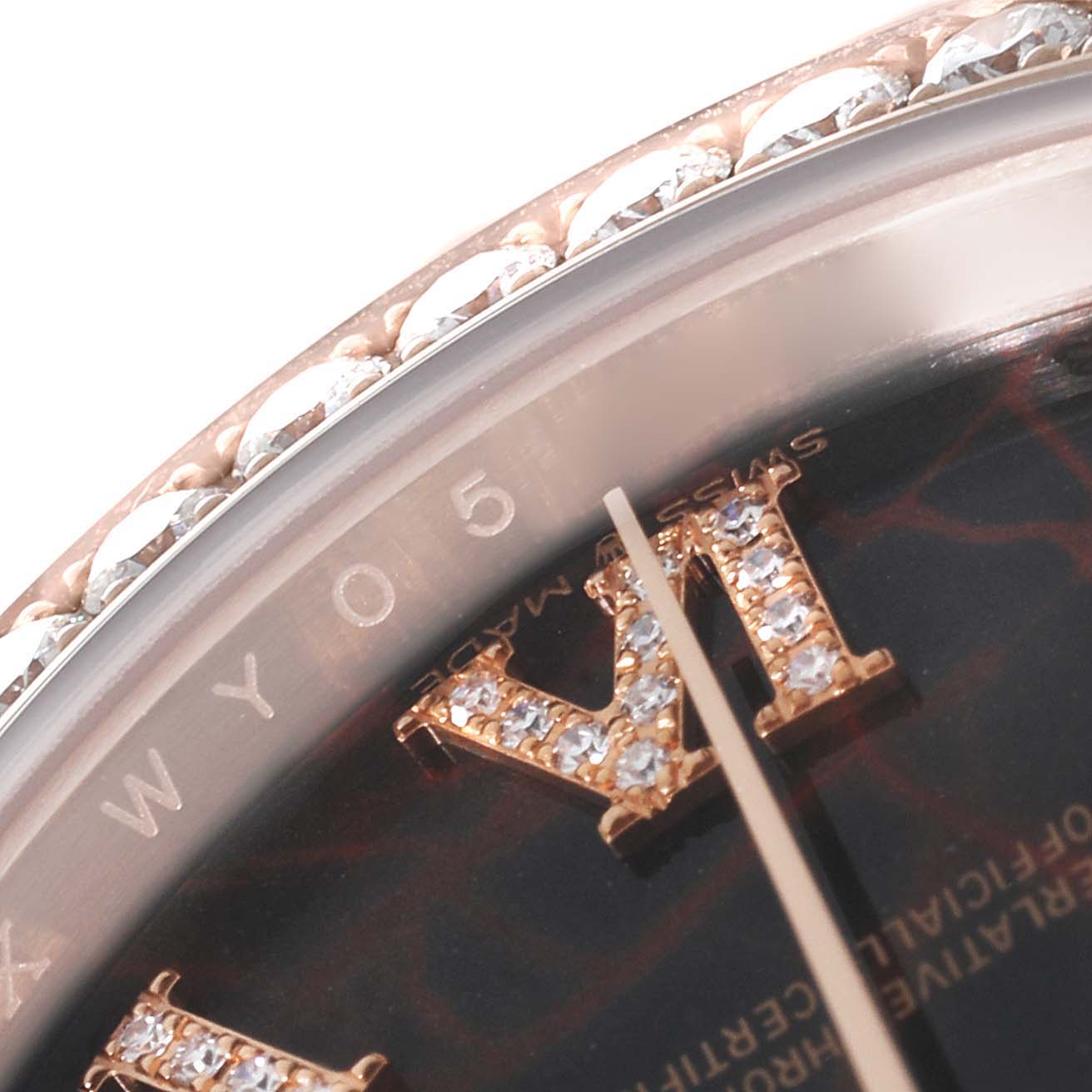 This close-up image of the Rolex President 128345 Men's Rose Gold Brown Dial 128345 Men's Rose Gold Brown Dial model shows part of the bezel with diamonds and the Roman numeral VI on the dial.