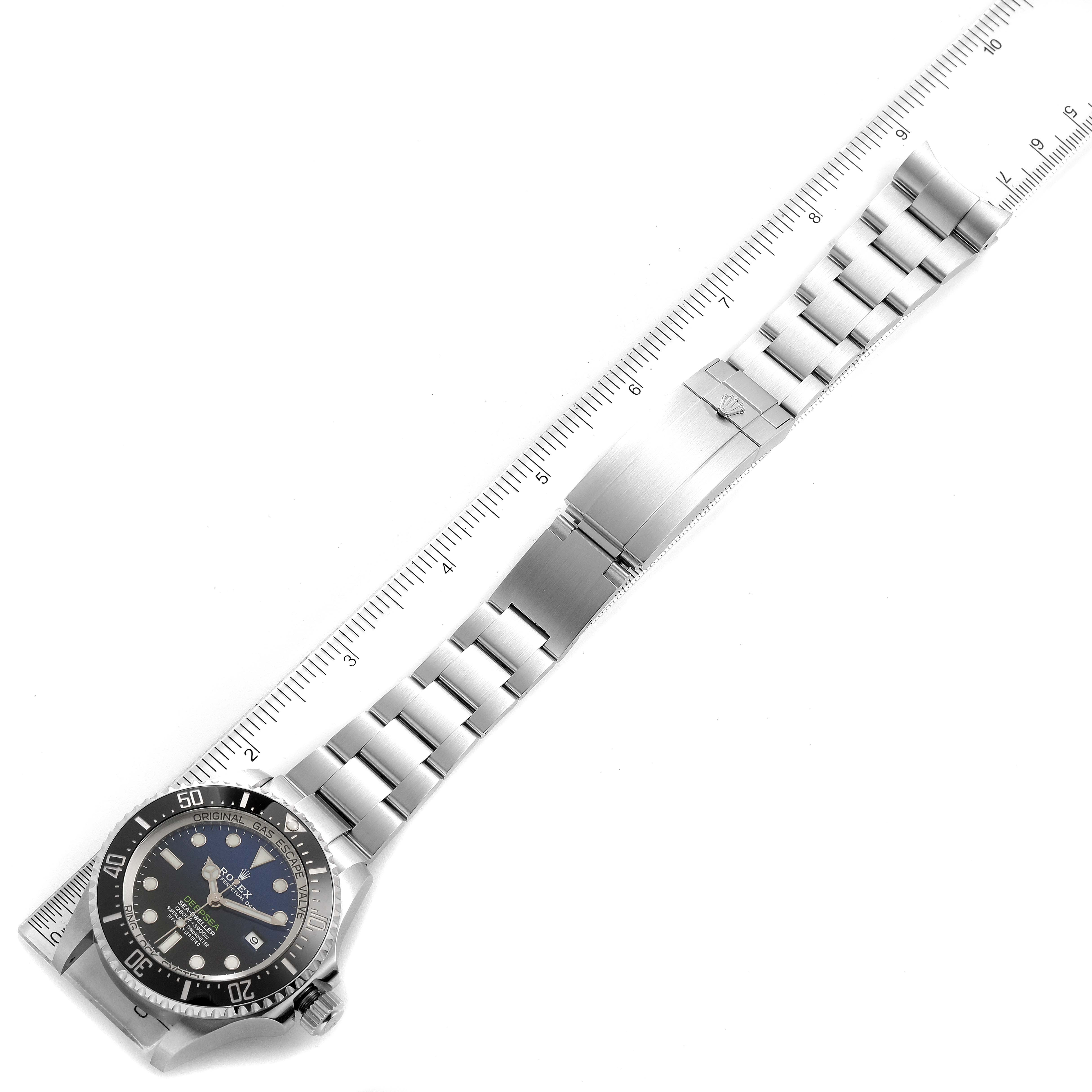 The image shows the Rolex Sea-Dweller 126660 Men
s Stainless Steel Blue Dial 126660 Men
s Stainless Steel Blue Dial watch laid flat next to a ruler, highlighting its face, bezel, and full metal bracelet.