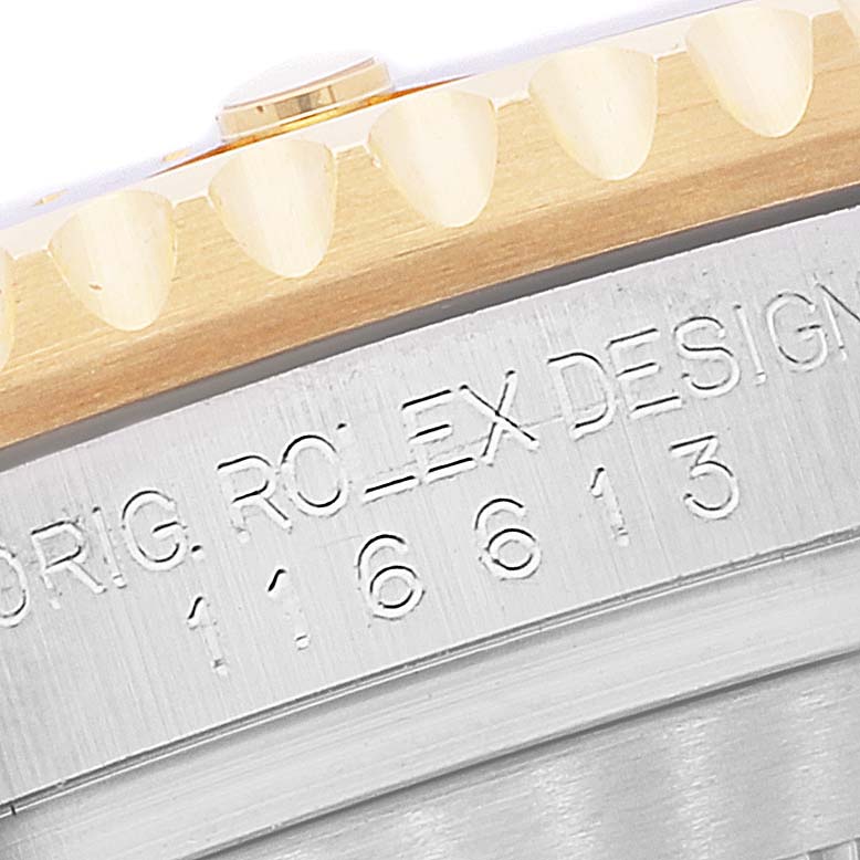 The image shows a close-up of the edge of a Rolex Submariner 116613 Men's Steel and Gold (two tone) Blue Dial 116613 Men's Steel and Gold (two tone) Blue Dial's bezel and part of the case with engraved details.