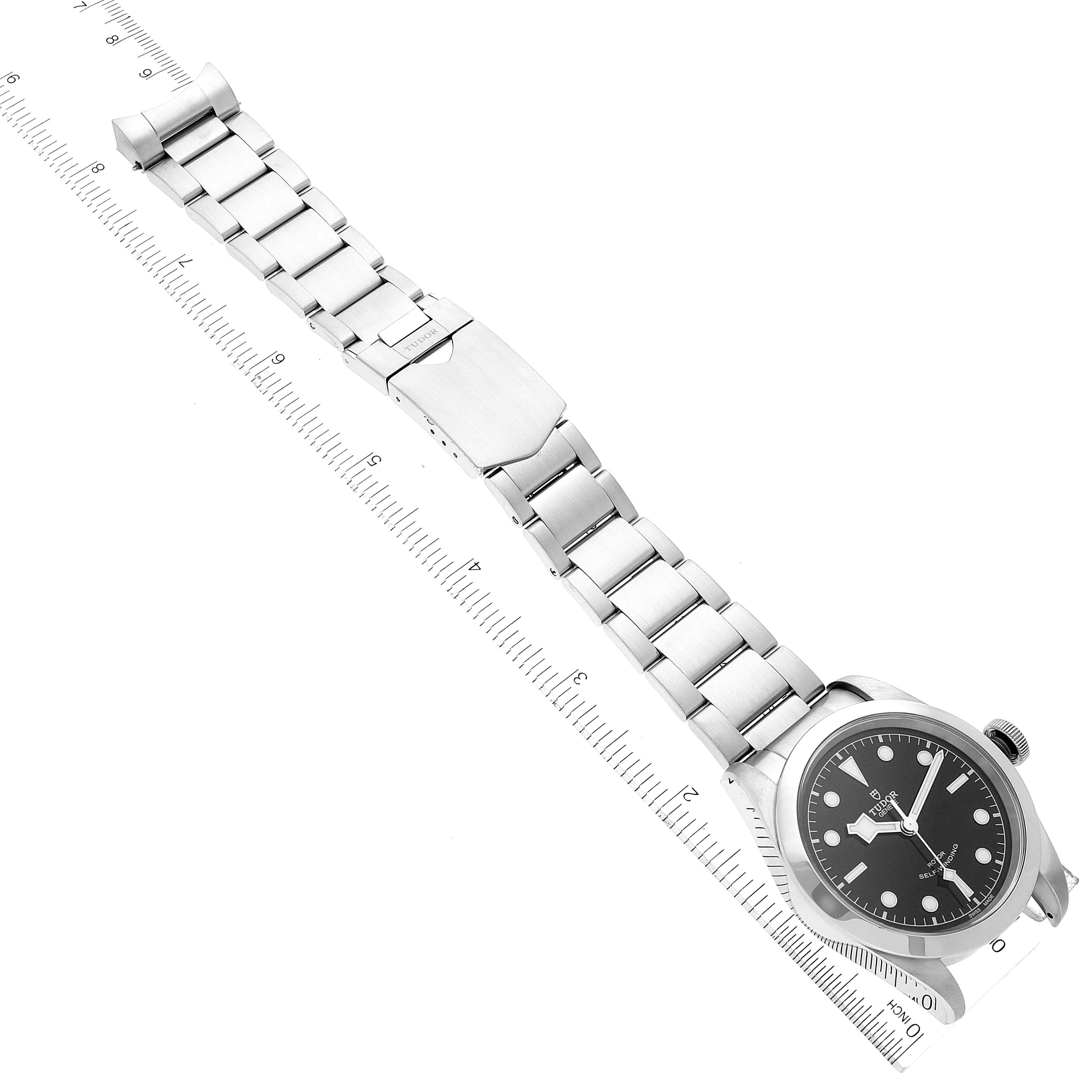 The image shows a Tudor Heritage Black Bay 79540 Men's Stainless Steel Black Dial 79540 Men's Stainless Steel Black Dial watch laid flat with its stainless steel bracelet extended and measured against a ruler.