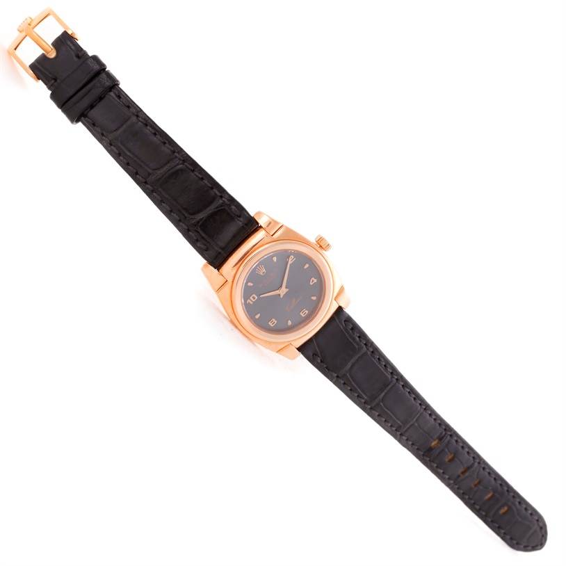 This image shows a top view of a Rolex Cellini 5310 Women's Rose Gold Grey Dial 5310 Women's Rose Gold Grey Dial watch with a black leather strap and a gold case.