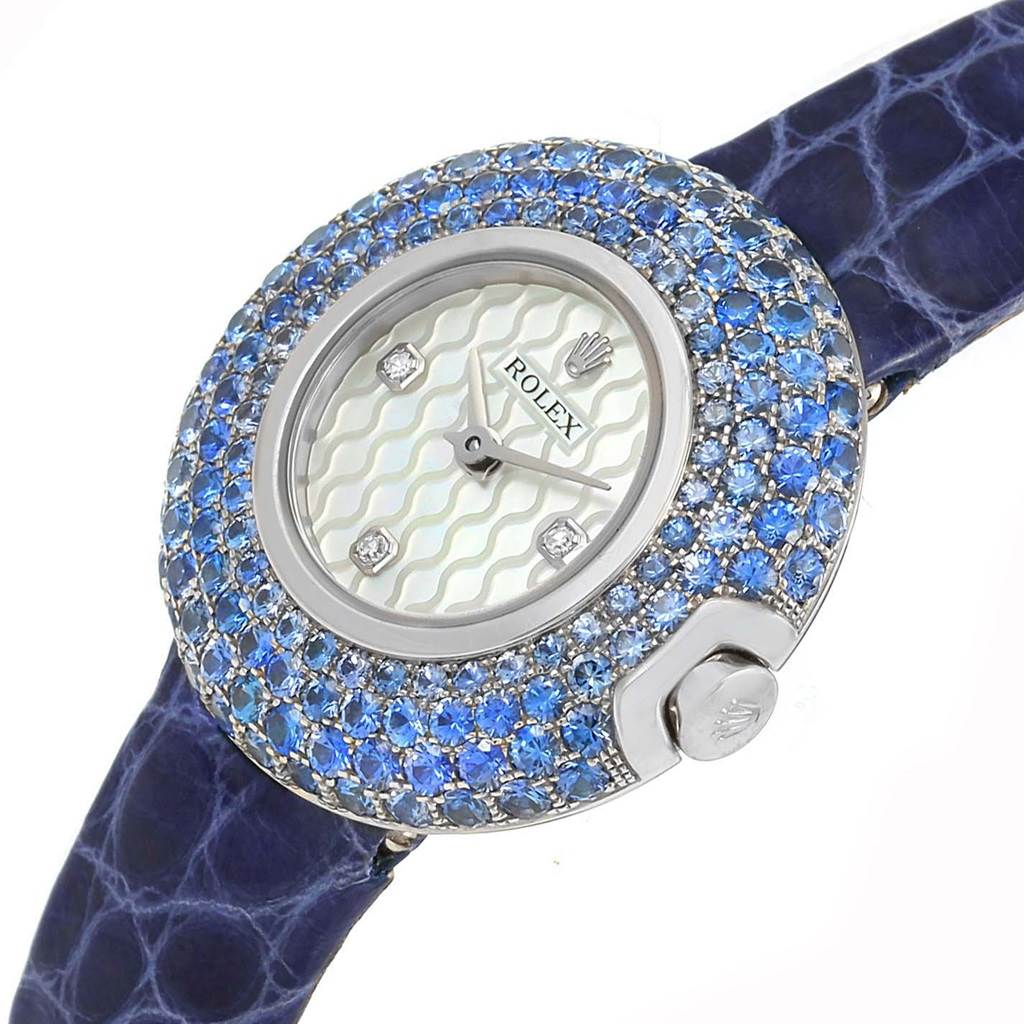 This image shows a Rolex Cellini 6201 Women's White Gold Mother of Pearl Dial 6201 Women's White Gold Mother of Pearl Dial watch from an angled top view, highlighting its blue gemstone-encrusted bezel, face, and strap.