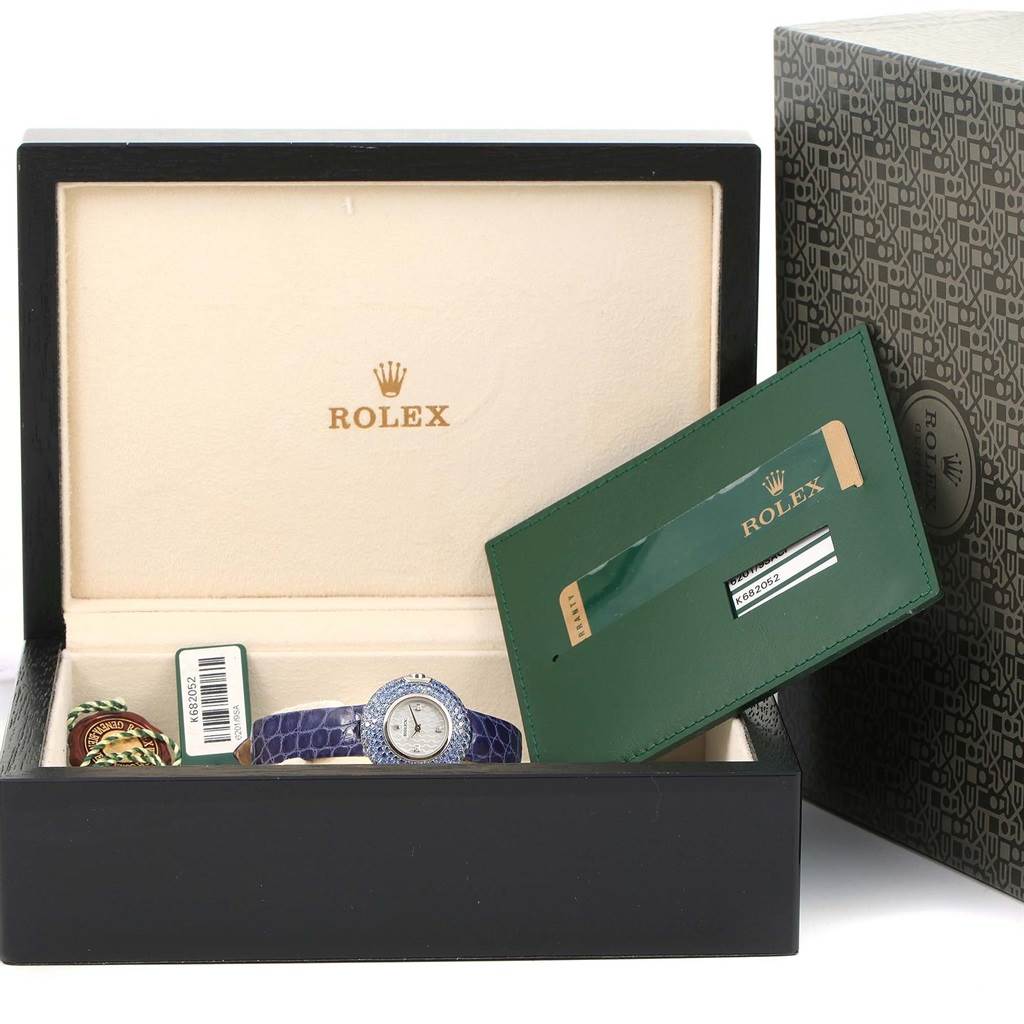 The image shows a Rolex Cellini 6201 Women's White Gold Mother of Pearl Dial 6201 Women's White Gold Mother of Pearl Dial watch and accessories at an angle inside an open box, along with a green certificate holder.