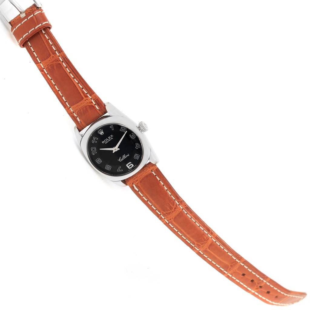 This Rolex Cellini 6229 Women's White Gold Black Dial 6229 Women's White Gold Black Dial watch is shown from a top-down angle, displaying its black dial, silver casing, and brown leather strap.