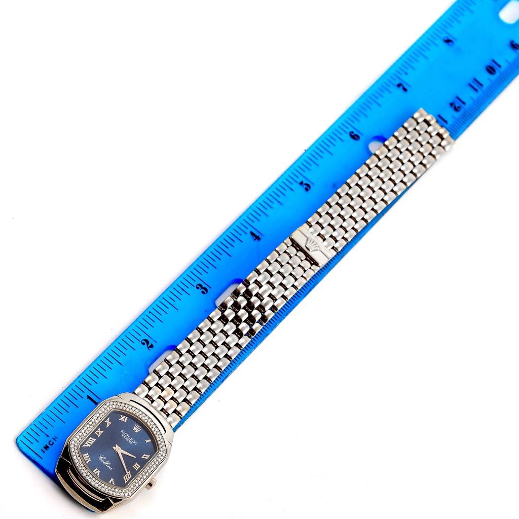 The image shows a Rolex Cellini 6691 Women
s White Gold Blue Dial 6691 Women
s White Gold Blue Dial watch laid flat next to a blue ruler, displaying its face, bracelet, and clasp.