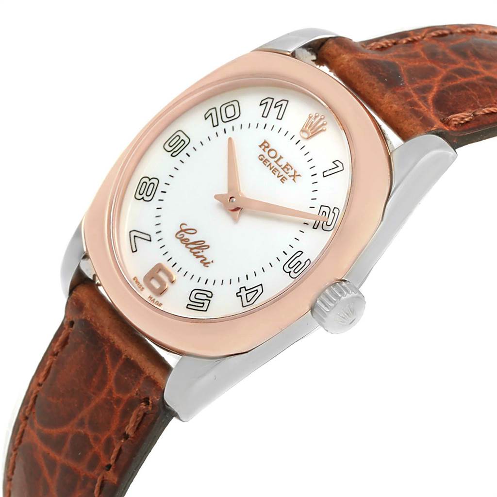 The image shows a slanted view of a Rolex Cellini 6229 Women's White Gold White Dial 6229 Women's White Gold White Dial watch showcasing its round dial, rose gold bezel, brown leather strap, and crown.