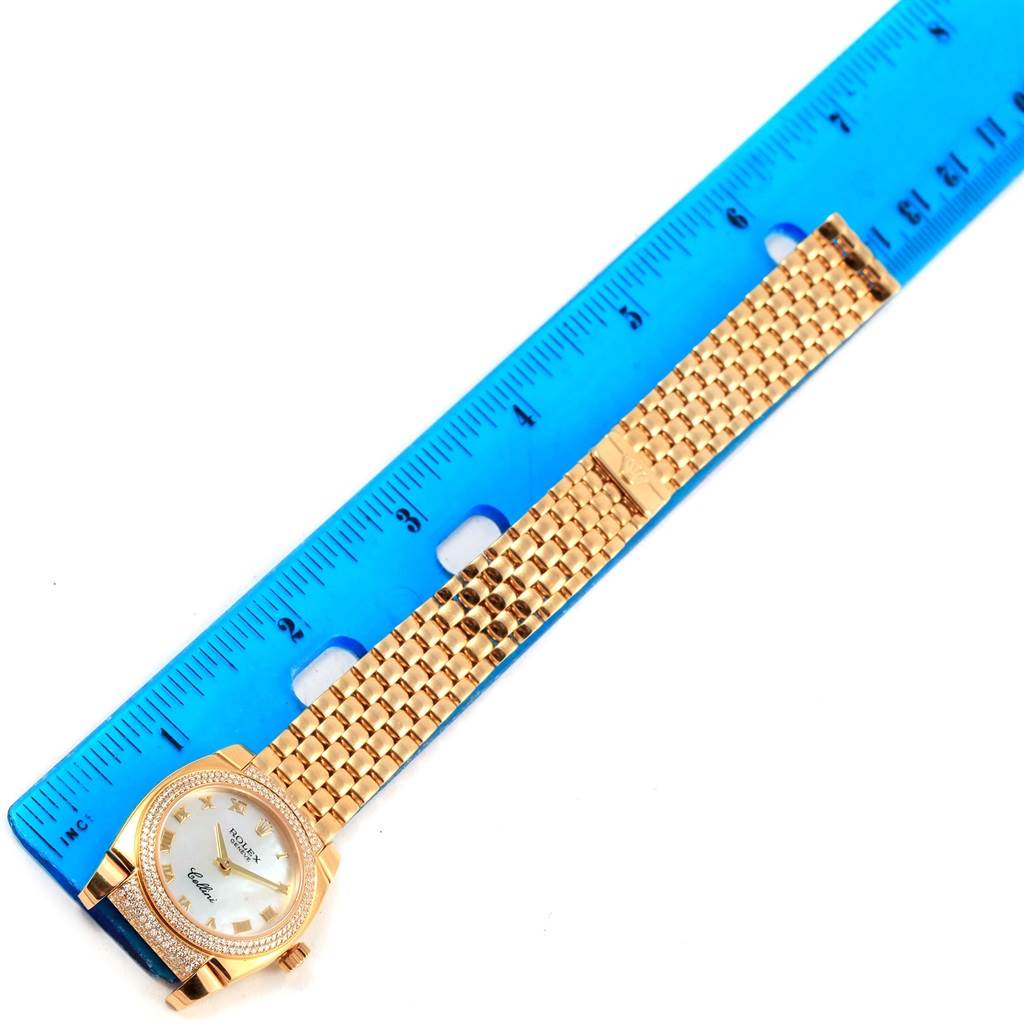 The image shows a top view of a Rolex Cellini 6311 Women's Yellow Gold Mother of Pearl Dial 6311 Women's Yellow Gold Mother of Pearl Dial watch with a gold bracelet laid next to a blue ruler.