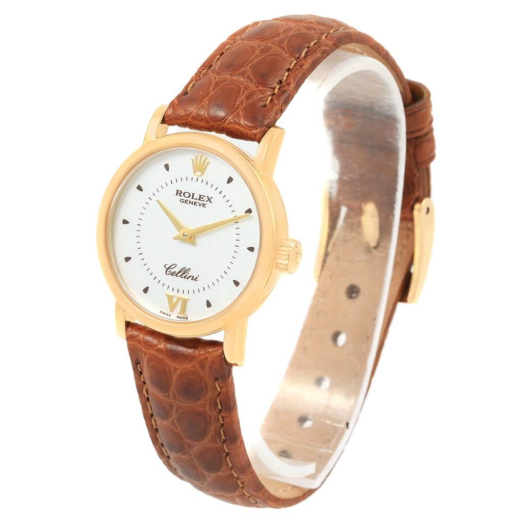 The Rolex Cellini 6610 Women's Yellow Gold Silver Dial 6610 Women's Yellow Gold Silver Dial watch is shown at a slight angle, highlighting its brown leather strap, white dial, and gold case.