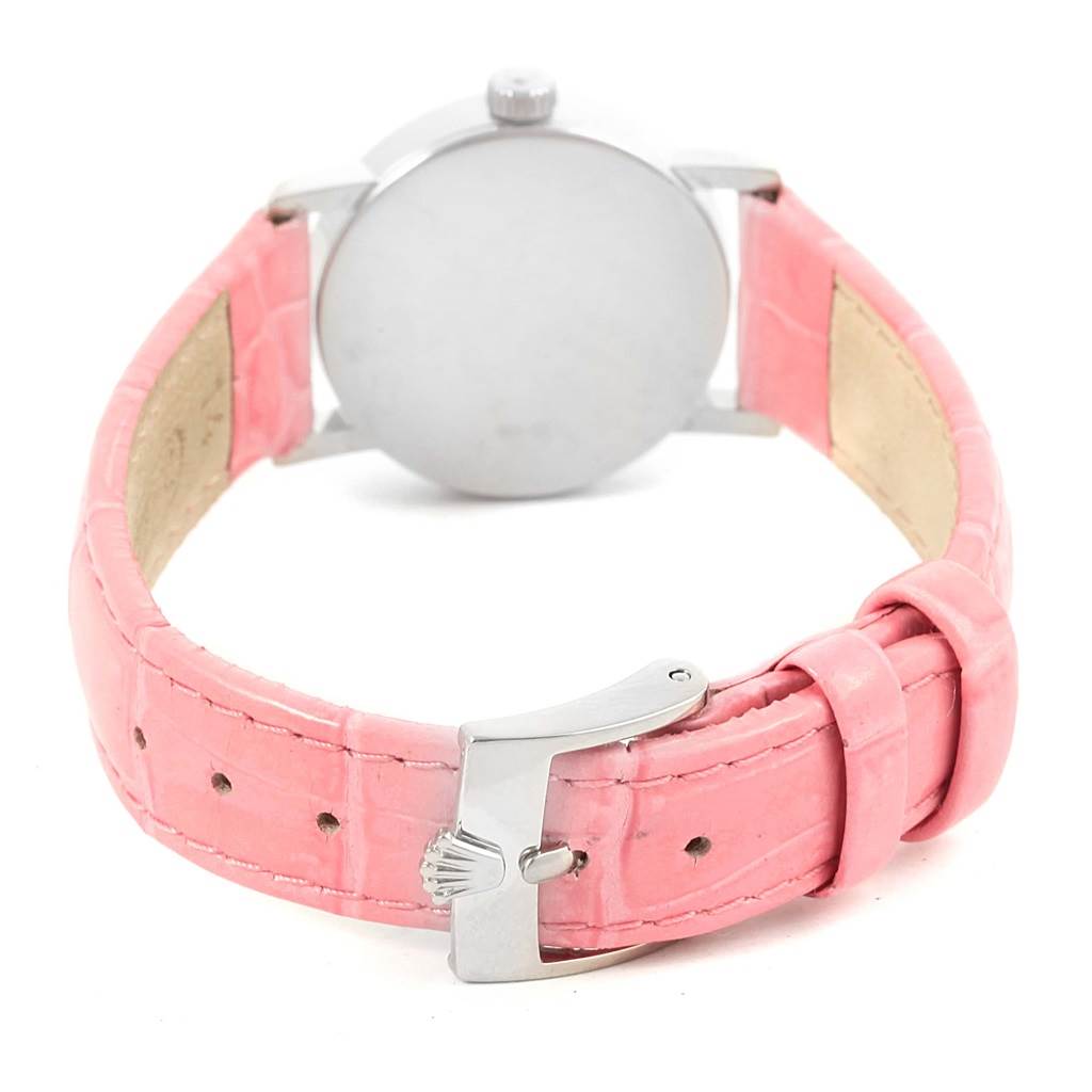 The image shows the back of a Rolex Cellini 6110 Women
s White Gold Silver Dial 6110 Women
s White Gold Silver Dial watch with a pink leather strap and a metal clasp featuring the Rolex logo.