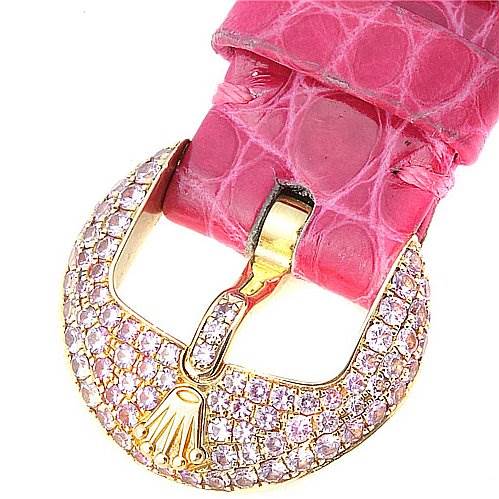 The image shows a close-up of the buckle on a Rolex Cellini 6201 Women's Yellow Gold Mother of Pearl Dial 6201 Women's Yellow Gold Mother of Pearl Dial watch, featuring a pink strap and a gold, diamond-encrusted clasp.