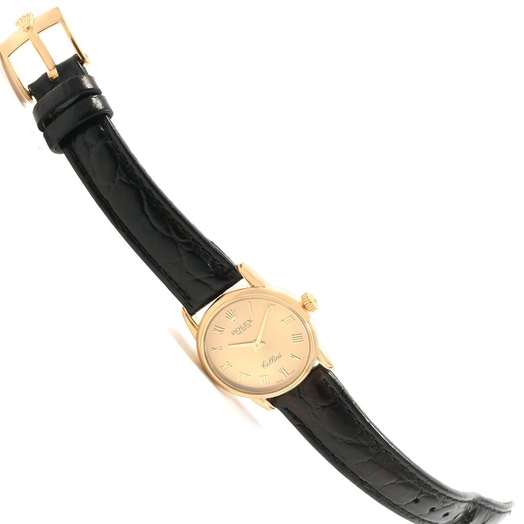 The image shows a Rolex Cellini 6111 Women's Yellow Gold Champagne Dial 6111 Women's Yellow Gold Champagne Dial watch from a slight top-down angle, highlighting its gold case, black leather strap, and buckle.