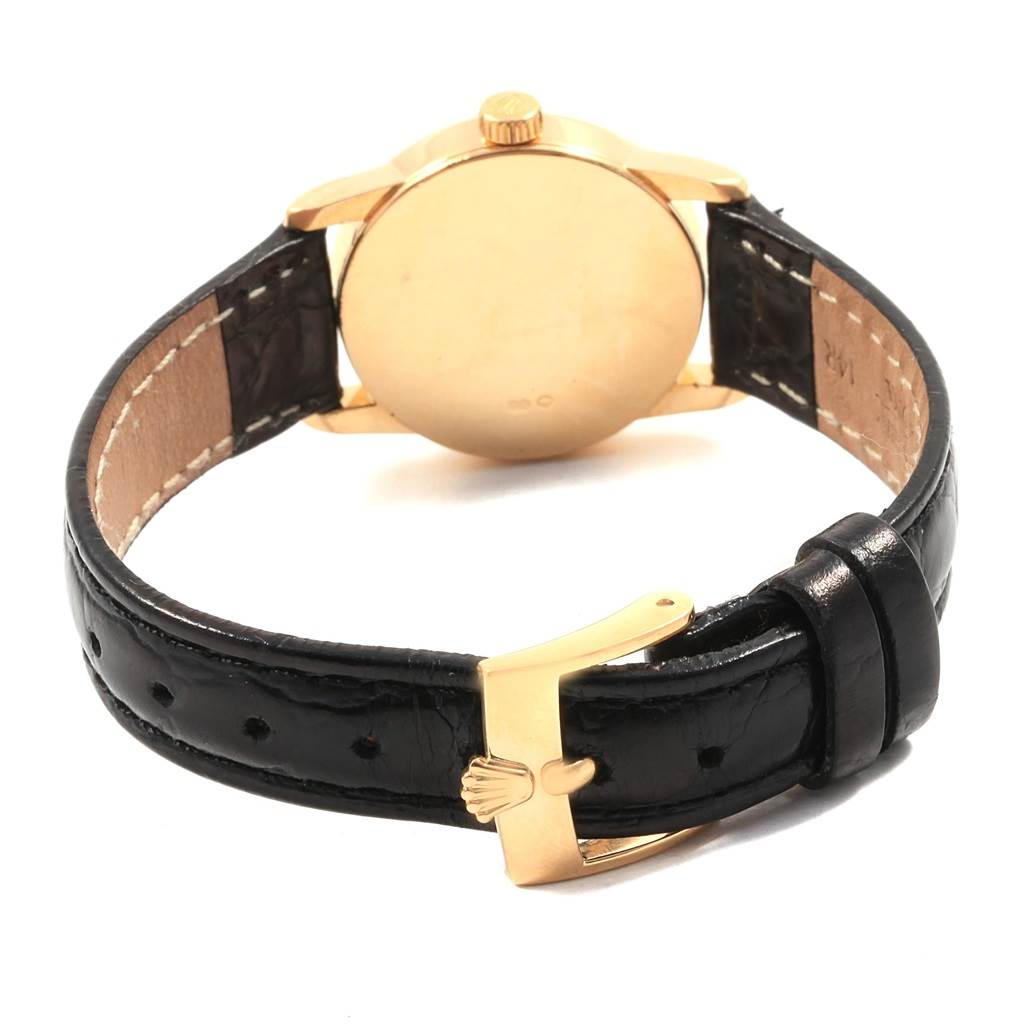 The image features the back view of a Rolex Cellini 6111 Women's Yellow Gold Champagne Dial 6111 Women's Yellow Gold Champagne Dial watch, showcasing its gold case and black leather strap with a gold buckle.