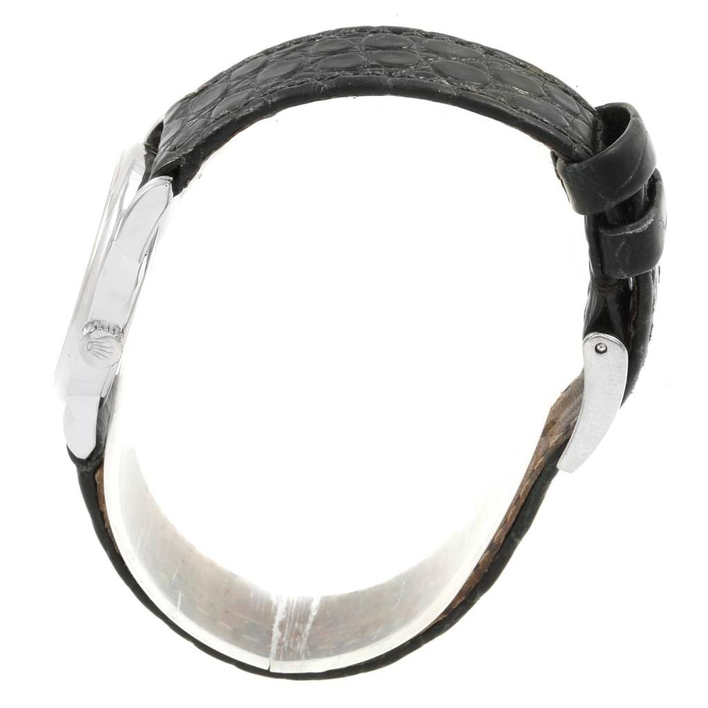 The image shows a side view of a Rolex Cellini 6111 Women's White Gold Black Dial 6111 Women's White Gold Black Dial watch, highlighting its case, crown, and leather strap with clasp.