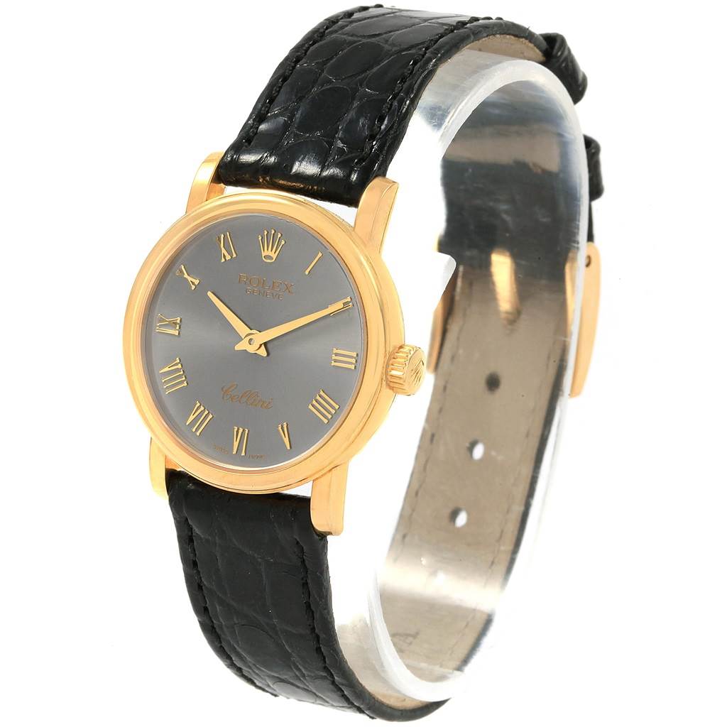 The Rolex Cellini 6110 Women
s Yellow Gold Grey Dial 6110 Women
s Yellow Gold Grey Dial watch is shown at a three-quarter angle, displaying its face, black leather strap, and gold casing.