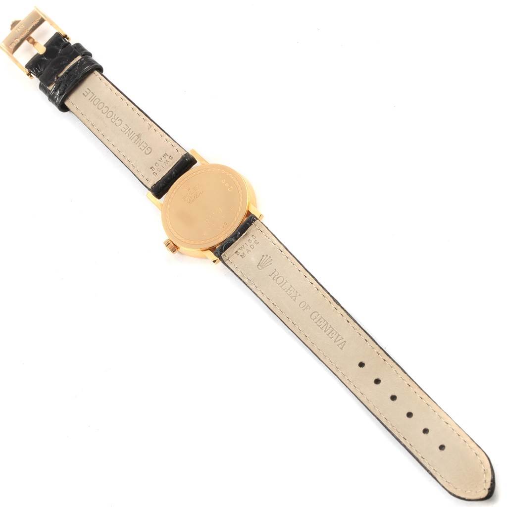 The image shows the backside of a Rolex Cellini 6110 Women
s Yellow Gold Grey Dial 6110 Women
s Yellow Gold Grey Dial watch, including the leather strap and the gold case back.