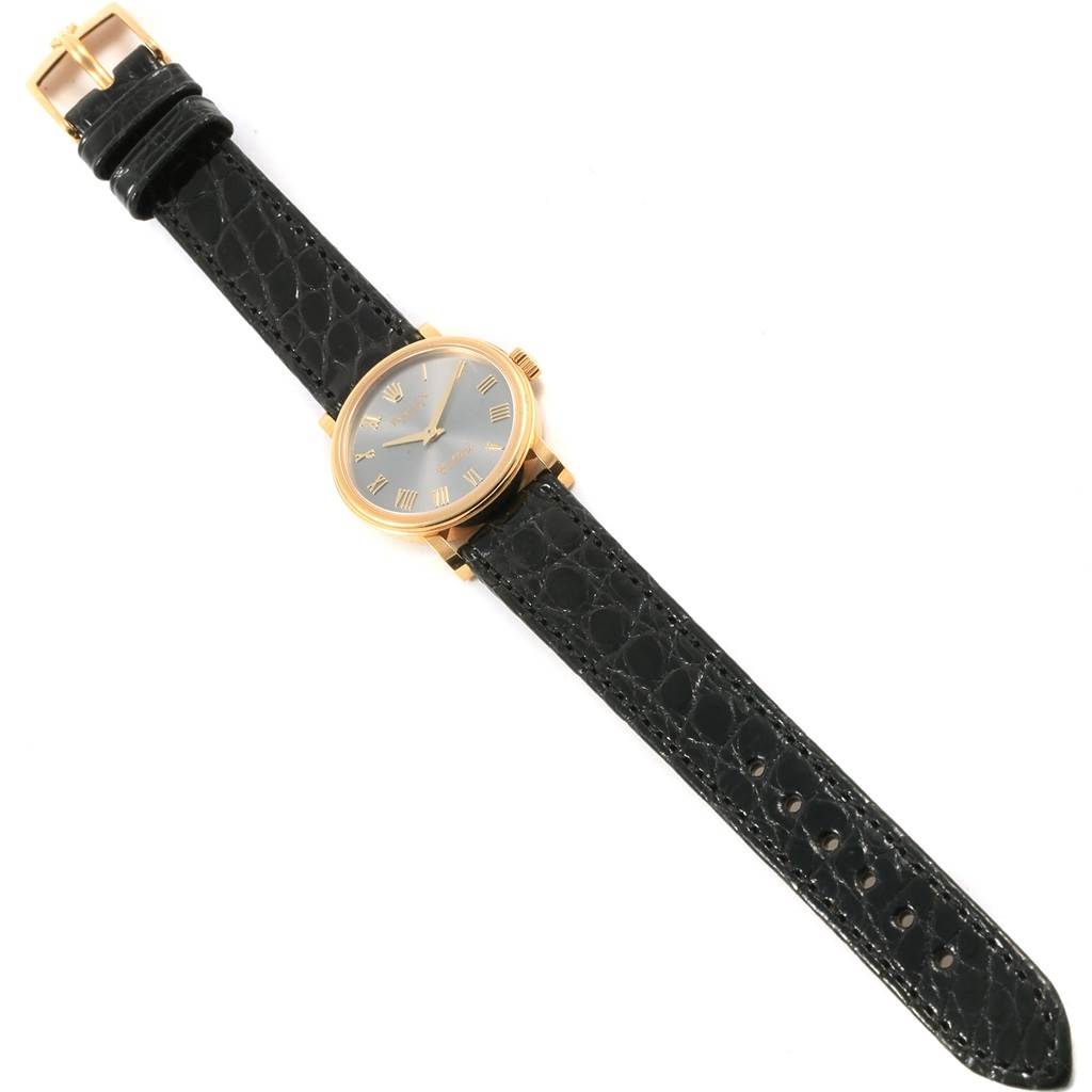 The image displays a Rolex Cellini 6110 Women
s Yellow Gold Grey Dial 6110 Women
s Yellow Gold Grey Dial watch from a top-down angle, showing the face, case, and black leather strap with a buckle.