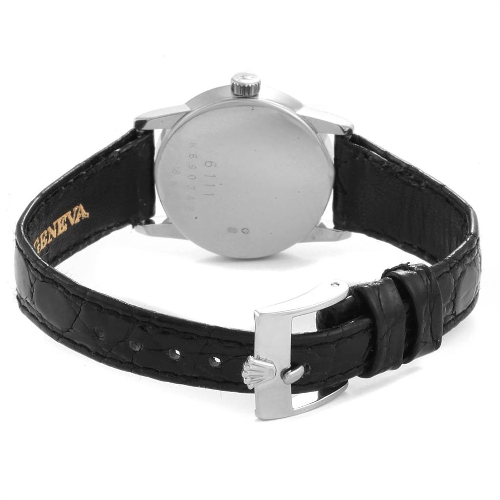 This image shows the back of a Rolex Cellini 6111 Women's White Gold Mother of Pearl Dial 6111 Women's White Gold Mother of Pearl Dial watch, featuring its case, crown, and a partially open black leather strap with a buckle.