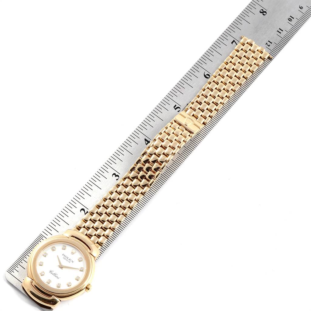 The image shows a top view of a Rolex Cellini 6622 Women
s Yellow Gold White Dial 6622 Women
s Yellow Gold White Dial watch laid next to a ruler, displaying the watch
s face and bracelet.