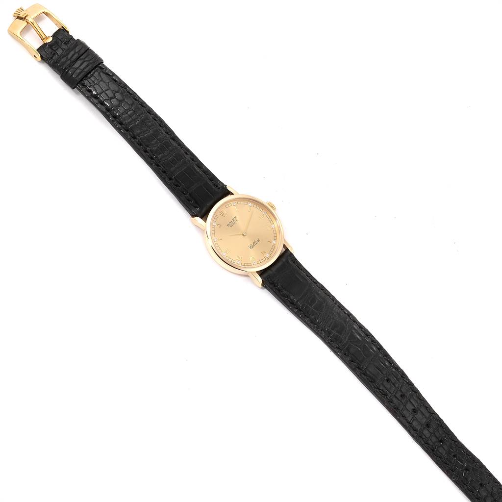 The image shows a top-down view of a Rolex Cellini 5109 Women's Yellow Gold Champagne Dial 5109 Women's Yellow Gold Champagne Dial watch with a gold dial and black leather strap.