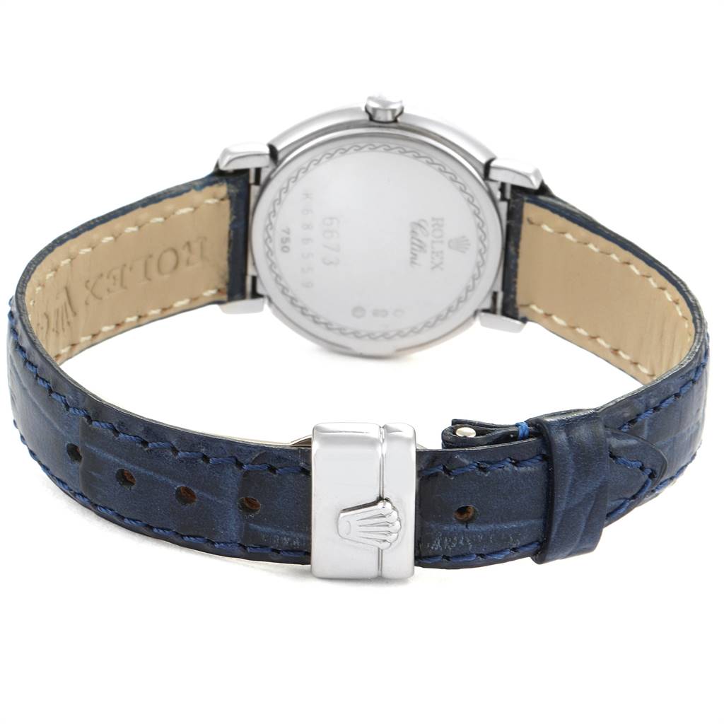 The image shows the back of a Rolex Cellini 6673 Women
s White Gold Silver Dial 6673 Women
s White Gold Silver Dial watch, featuring its case back, blue leather strap, and clasp.
