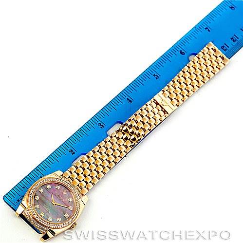 The Rolex Cellini 6321 Women
s Yellow Gold Mother of Pearl Dial 6321 Women
s Yellow Gold Mother of Pearl Dial watch is shown from a top-down angle, featuring the face, bezel, and full bracelet next to a blue ruler for size reference.