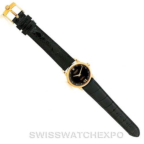 This is a top-down view of a Rolex Cellini 6111 Women's Yellow Gold Black Dial 6111 Women's Yellow Gold Black Dial watch, showcasing its black strap and round gold case.