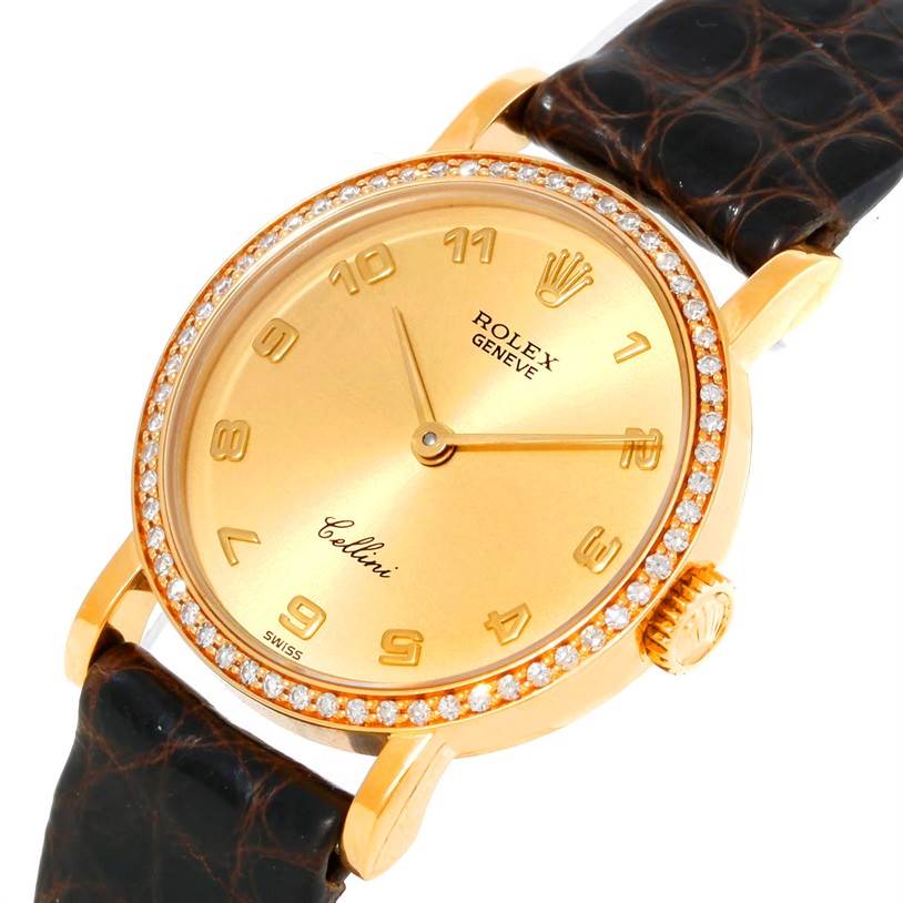 This image shows a Rolex Cellini 5113 Women's Yellow Gold Champagne Dial 5113 Women's Yellow Gold Champagne Dial watch at a slight angle, highlighting the gold dial, diamond-studded bezel, and leather strap.