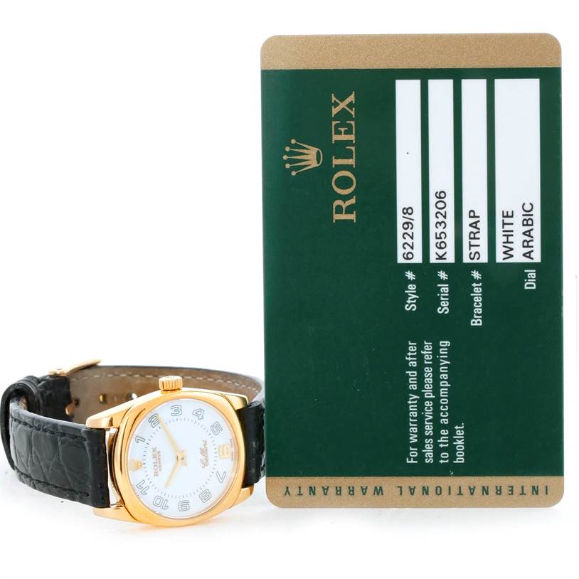 The image shows the Rolex Cellini 6229 Women's Yellow Gold White Dial 6229 Women's Yellow Gold White Dial watch at an oblique angle, alongside its official warranty card.