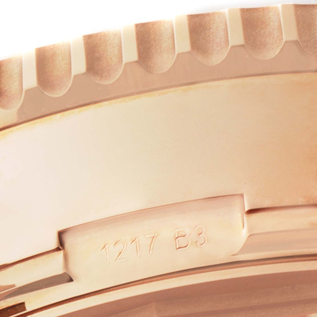 This close-up shows a part of the bezel and case side of a Breitling Navitimer RB031121/Q619-252S Men's Rose Gold Brown Dial RB031121/Q619-252S Men's Rose Gold Brown Dial watch with some engraved markings.
