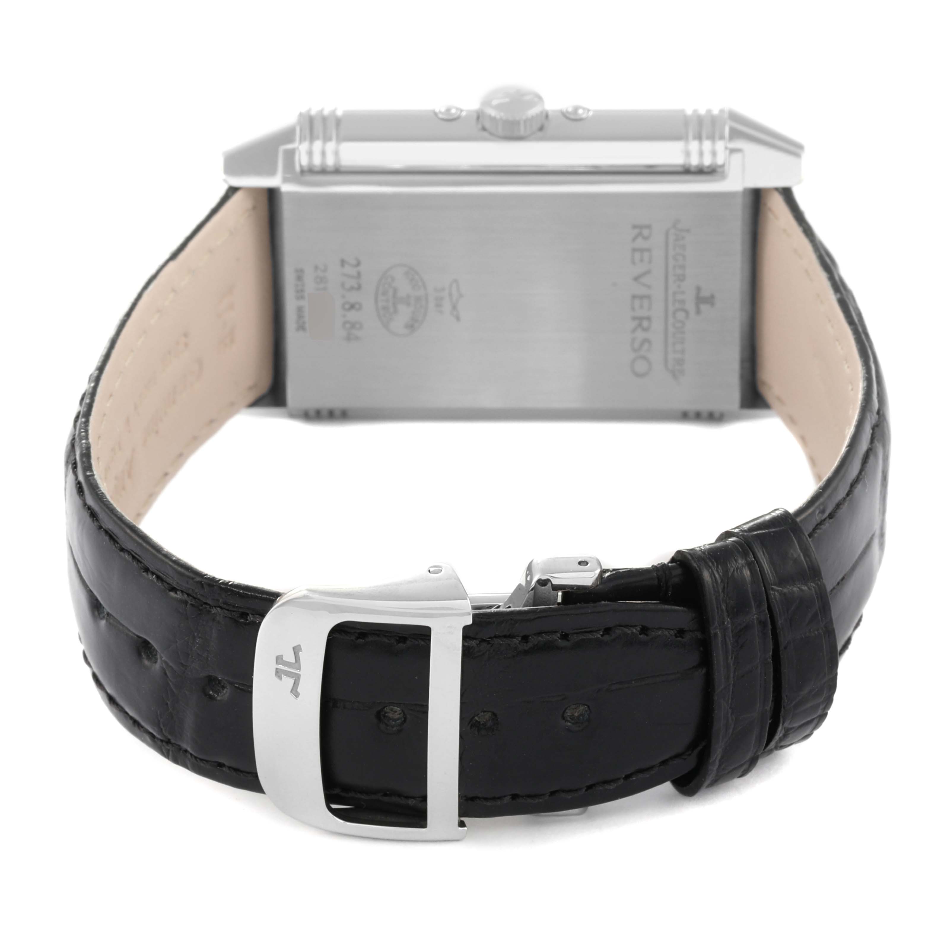 The image shows the back of a Jaeger-LeCoultre Reverso watch, highlighting the case back and leather strap with buckle.