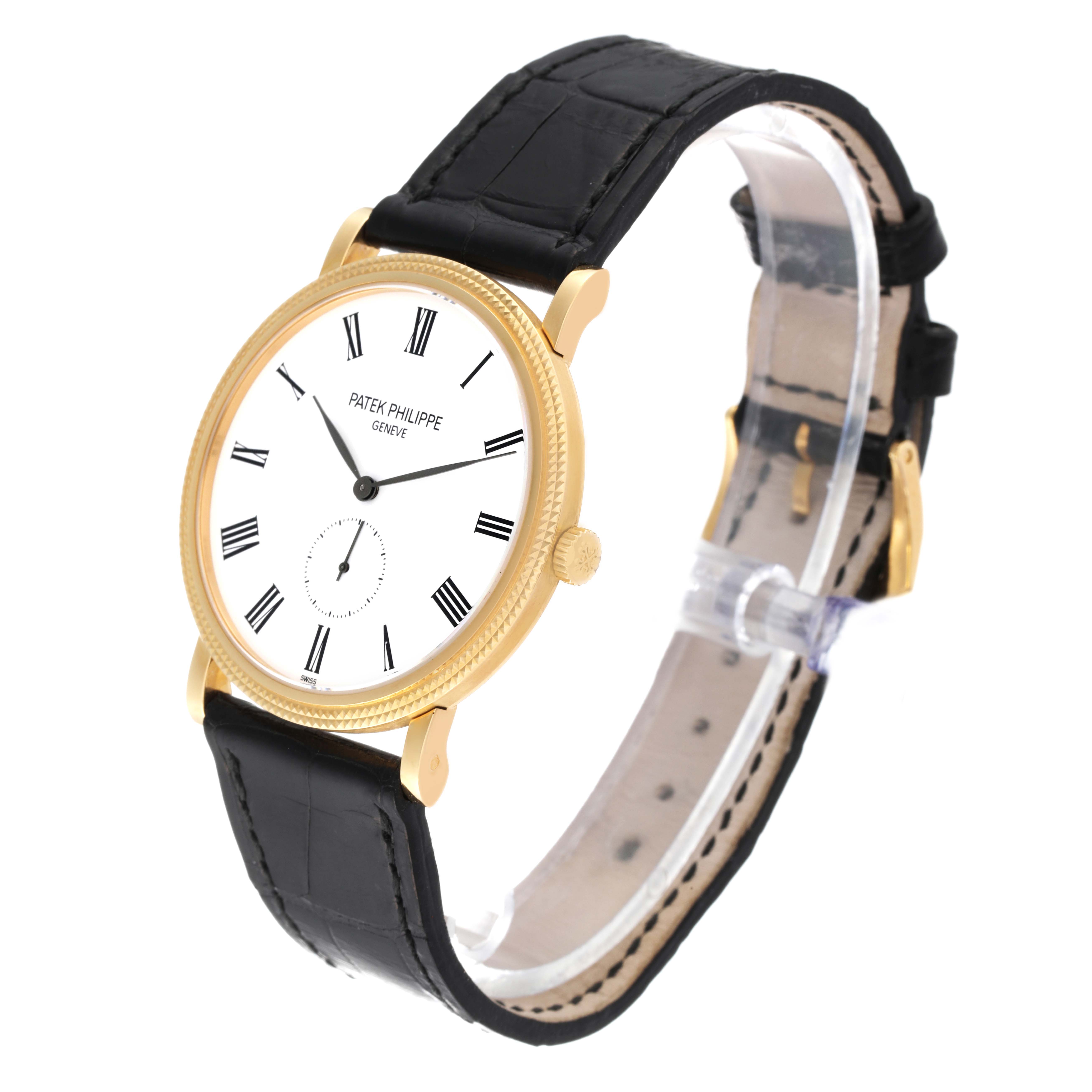 The image shows a Patek Philippe Calatrava 5119J Men
s Yellow Gold White Dial 5119J Men
s Yellow Gold White Dial watch at an oblique angle, highlighting its gold case, white dial, and black leather strap.