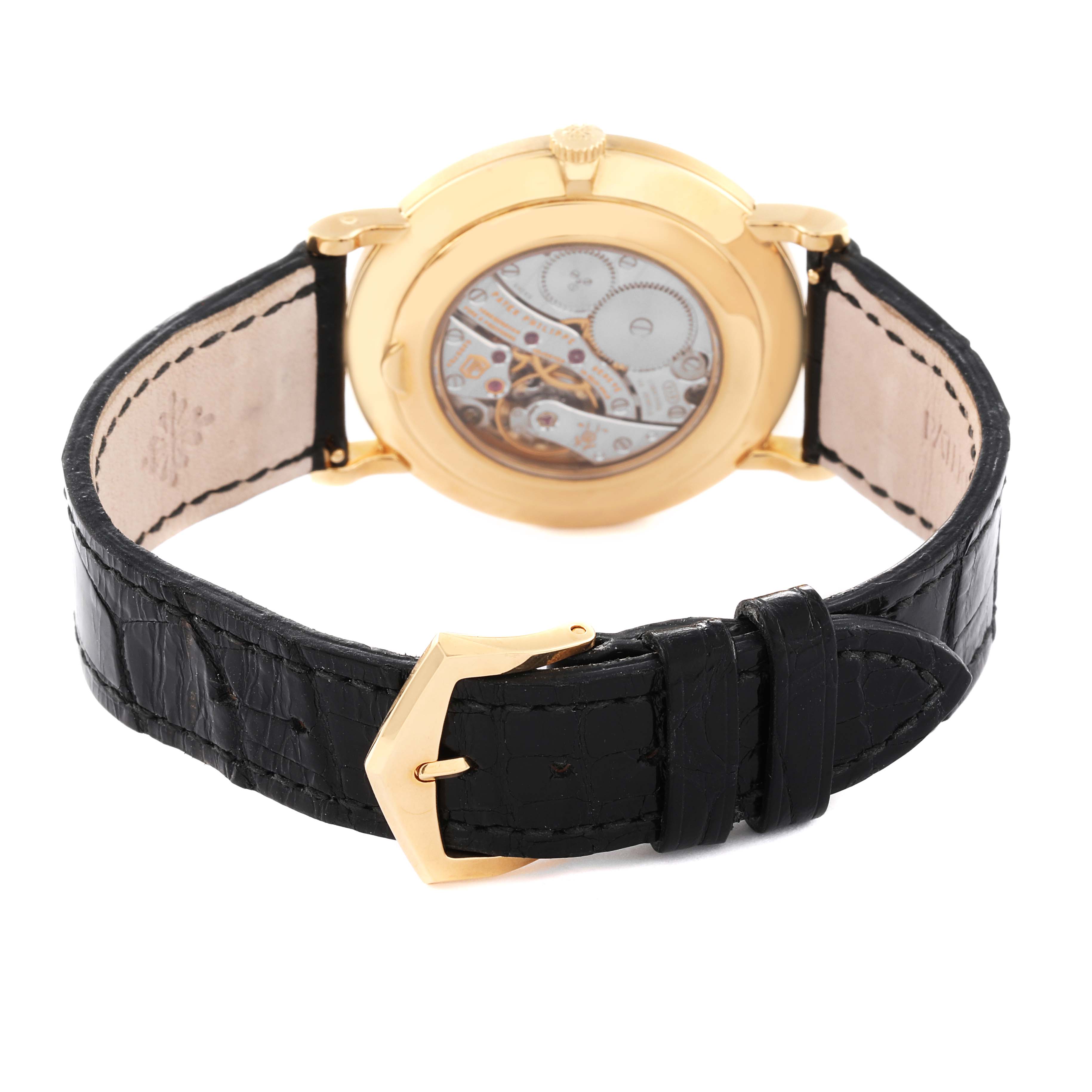The image shows the back view of a Patek Philippe Calatrava 5119J Men
s Yellow Gold White Dial 5119J Men
s Yellow Gold White Dial watch, highlighting its intricate mechanism and black leather strap.
