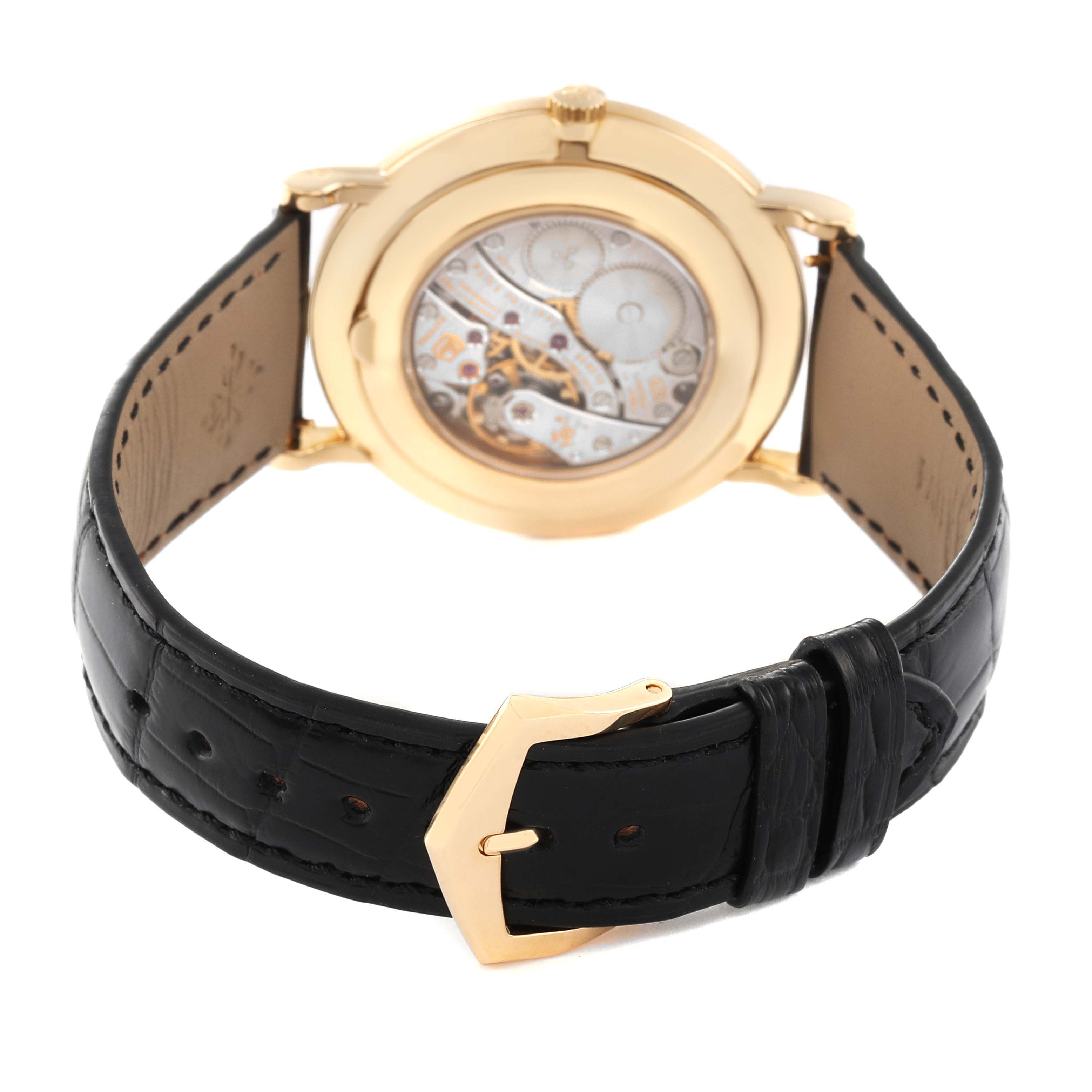The image shows the back view of a Patek Philippe Calatrava 5119J Men's Yellow Gold White Dial 5119J Men's Yellow Gold White Dial watch, displaying its movement and black leather strap with a gold buckle.