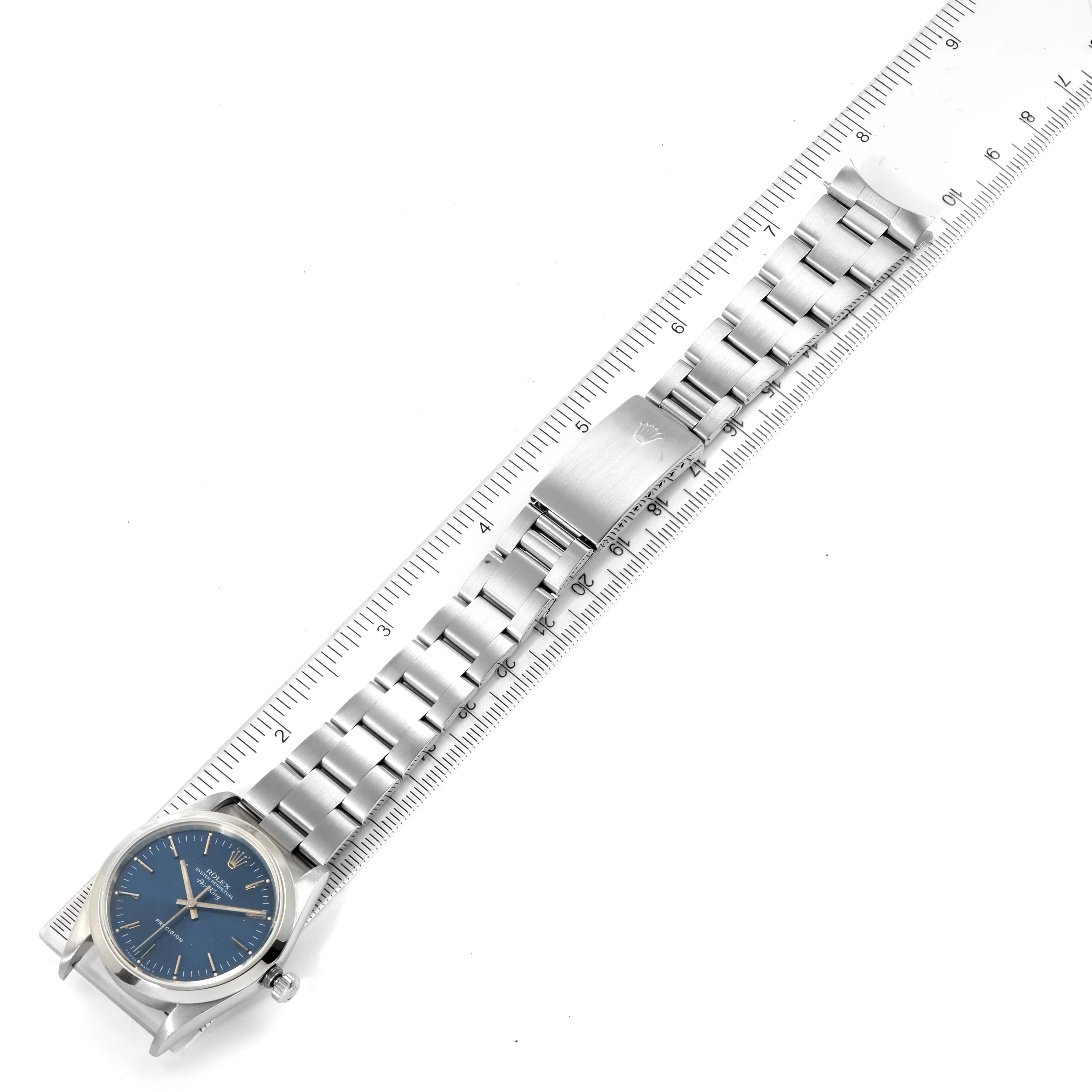 The image shows a top-down view of a Rolex Air-King 14000 Men's Stainless Steel Blue Dial 14000 Men's Stainless Steel Blue Dial watch next to a ruler, displaying its face and bracelet.