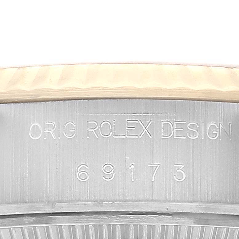 This close-up image shows the side profile of a Rolex Datejust 69173 Women's Steel and Gold (two tone) Champagne Dial 69173 Women's Steel and Gold (two tone) Champagne Dial watch, specifically the bezel and part of the case, featuring engraved text.