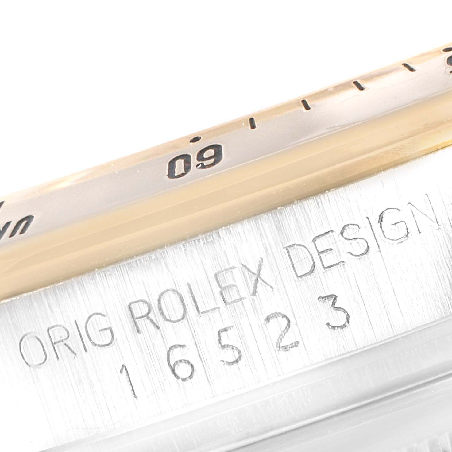 This image shows a close-up angle of the bezel and case of a Rolex Daytona 16523 Men
s Steel and Gold (two tone) Champagne Dial 16523 Men
s Steel and Gold (two tone) Champagne Dial, with the model number and "Rolex Design" engraving visible.