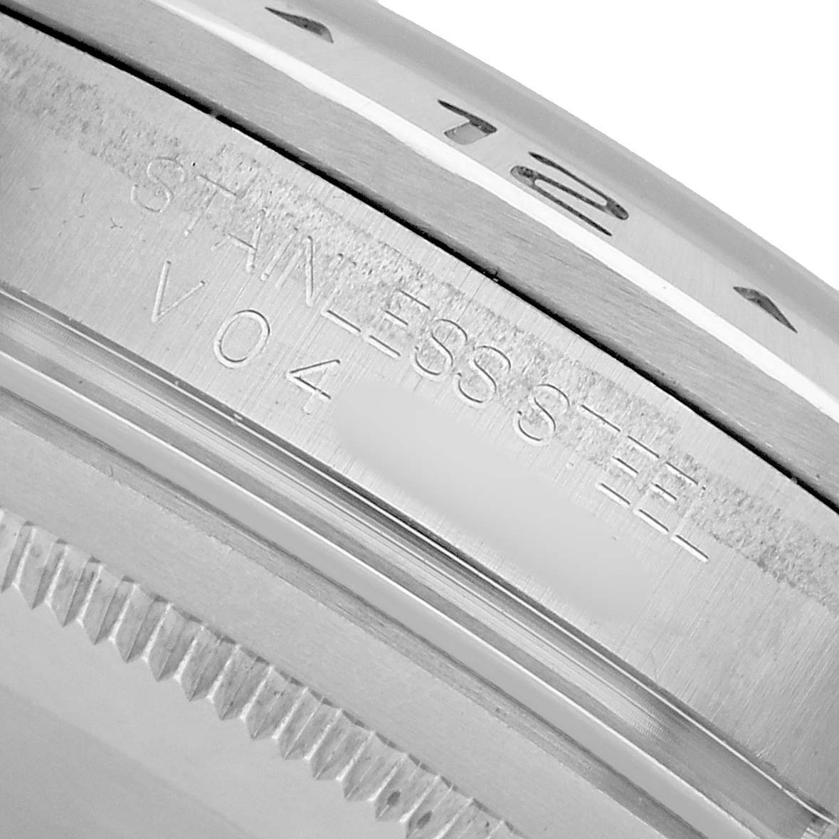 The image shows a close-up of the stainless steel side and engraved details of a Rolex Explorer 16570 Men's Stainless Steel White Dial watch's bezel.