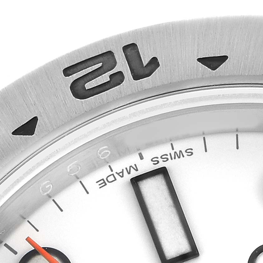 The image shows a close-up of the top part of a Rolex Explorer 216570 Men's Stainless Steel White Dial watch, highlighting the bezel and a part of the dial.