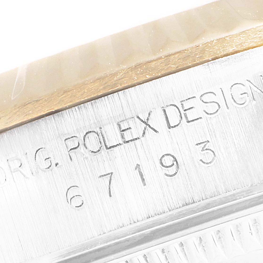 This close-up image shows the side of the case and part of the bezel with engravings on a Rolex Oyster Perpetual 67193 Women's Steel and Gold (two tone) Champagne Dial 67193 Women's Steel and Gold (two tone) Champagne Dial watch.