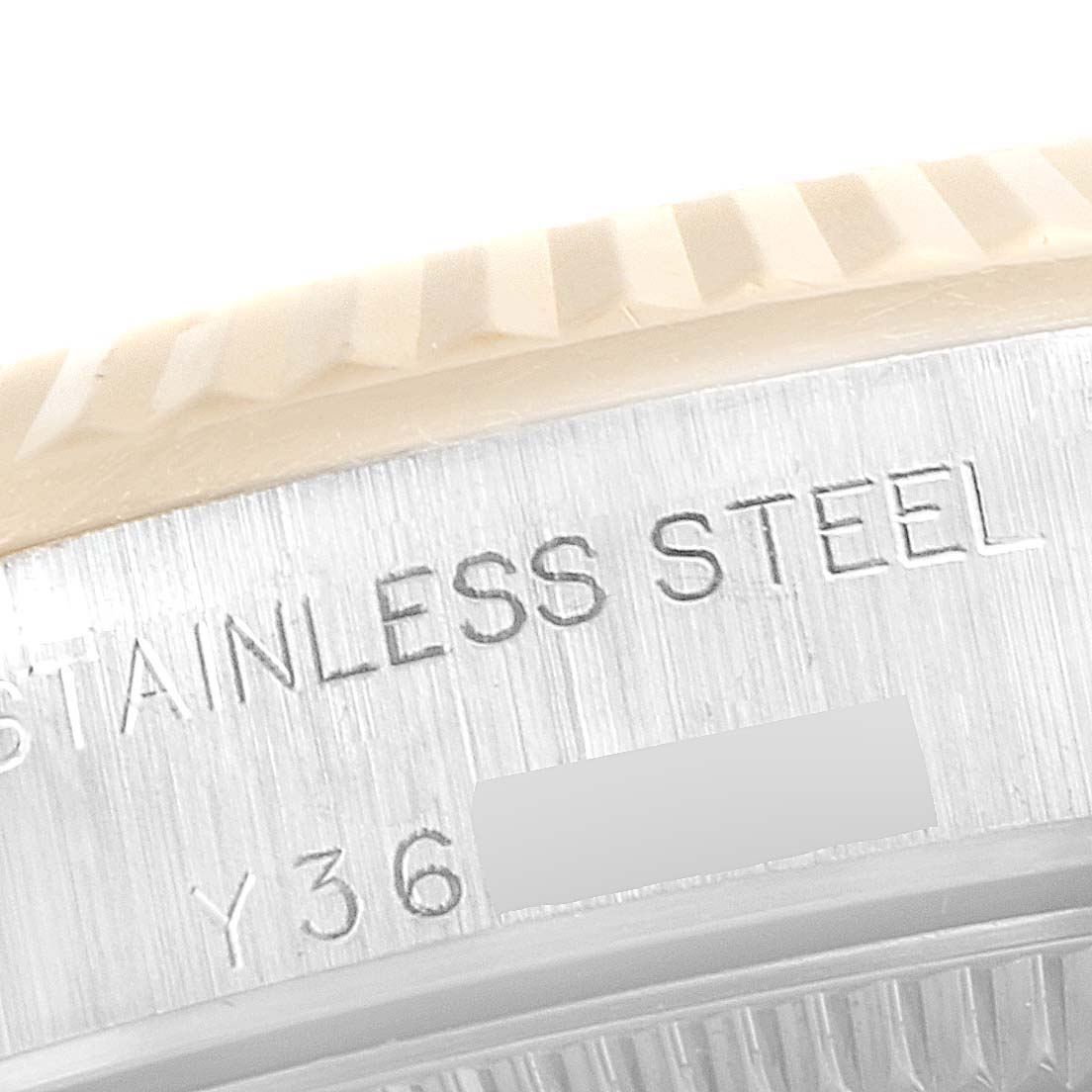 This close-up shows the engraved stainless steel back case and part of the bezel of a Rolex Oyster Perpetual 76193 Women's Steel and Gold (two tone) Silver Dial 76193 Women's Steel and Gold (two tone) Silver Dial watch.