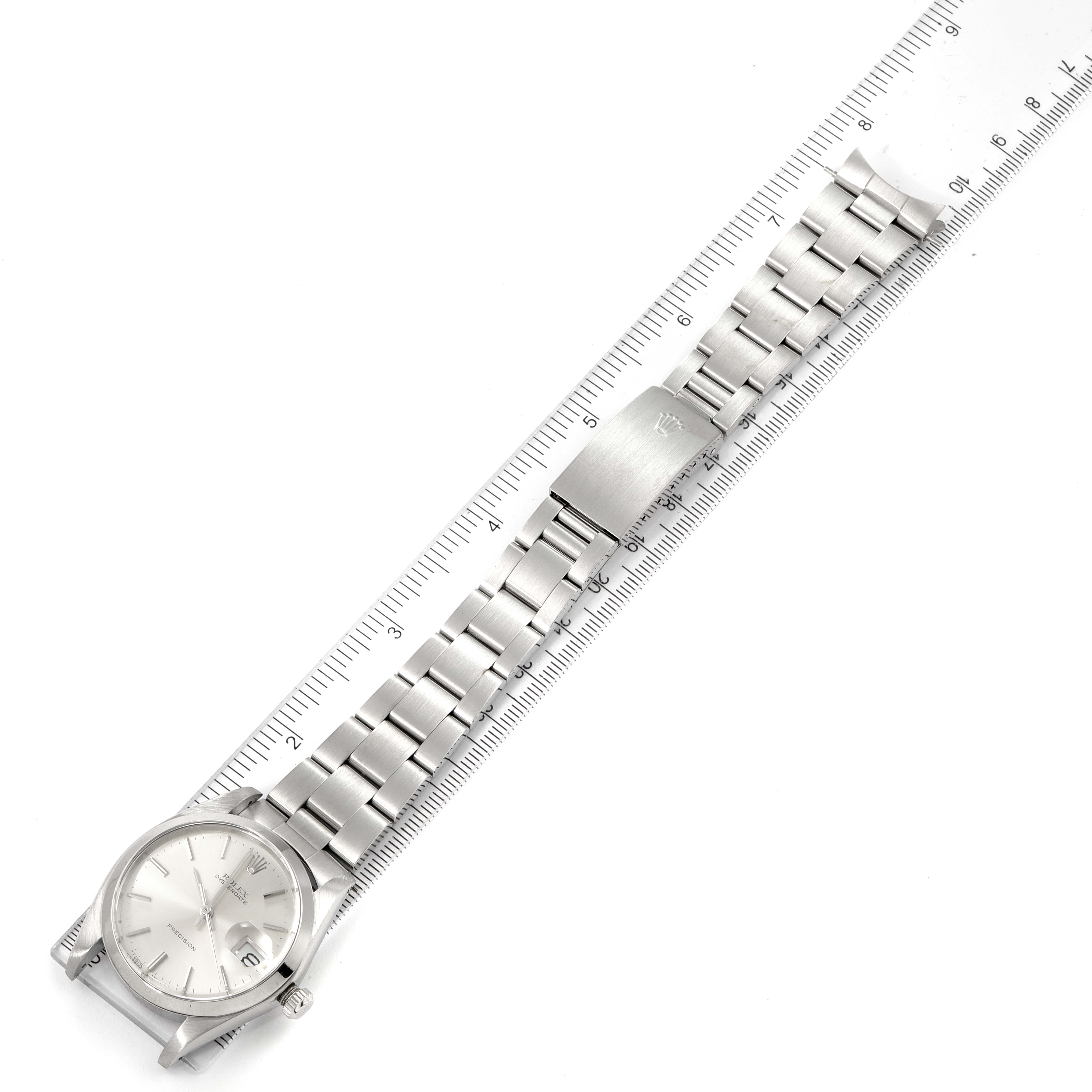 The image shows a top view of a Rolex Vintage Collection 6694 Men's Stainless Steel Silver Dial 6694 Men's Stainless Steel Silver Dial watch with a metal band next to a ruler for measurement.