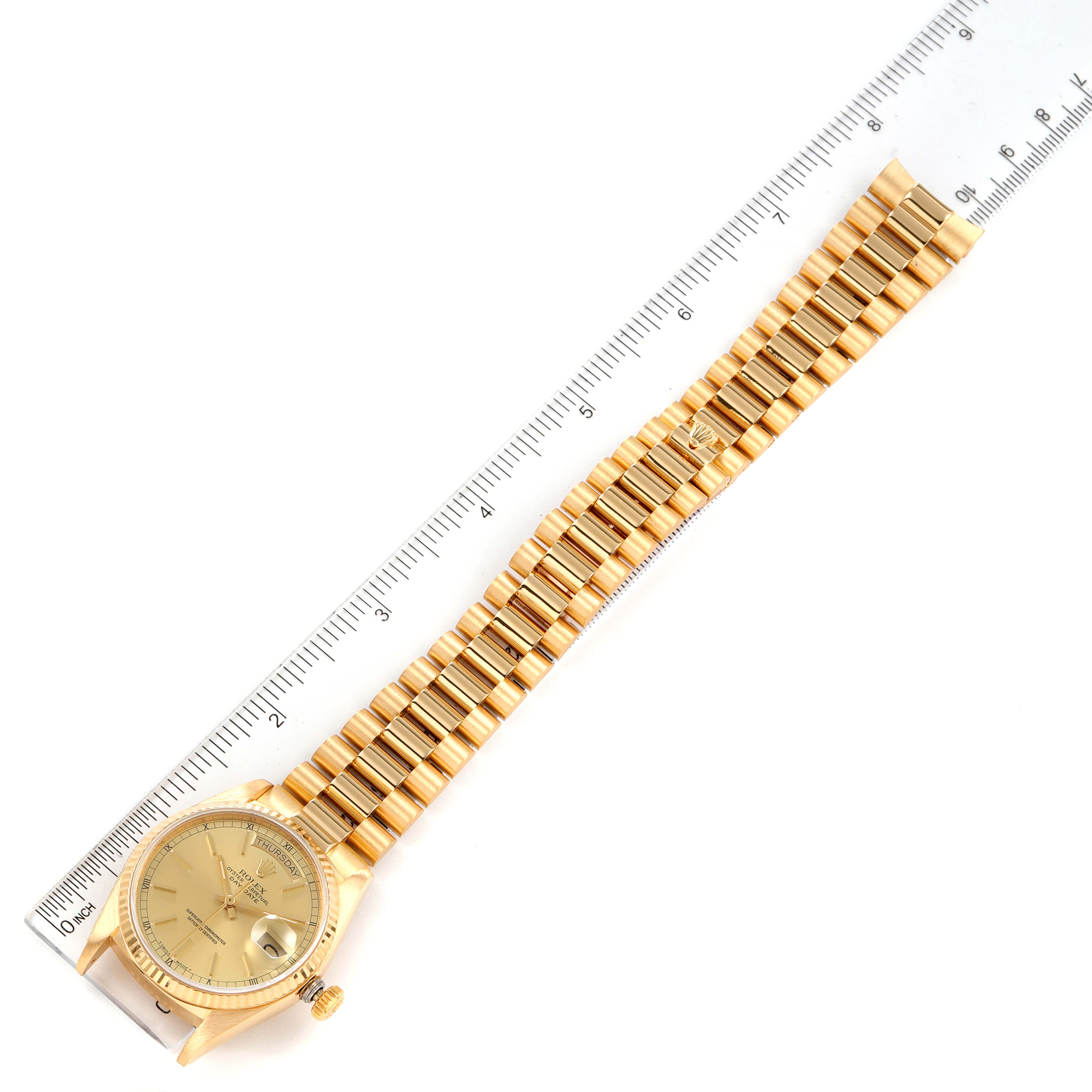 This image shows a gold Rolex President 18038 Men's Yellow Gold Champagne Dial 18038 Men's Yellow Gold Champagne Dial model watch placed next to a metric ruler for scale, displaying the watch face and bracelet.