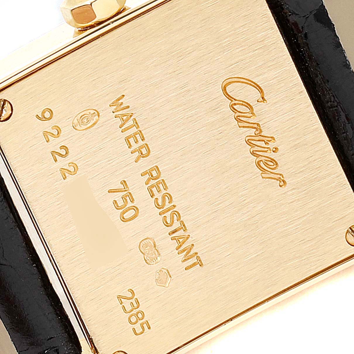 The image shows the back of a Tank Francaise watch by Cartier, highlighting engravings and a portion of the strap.