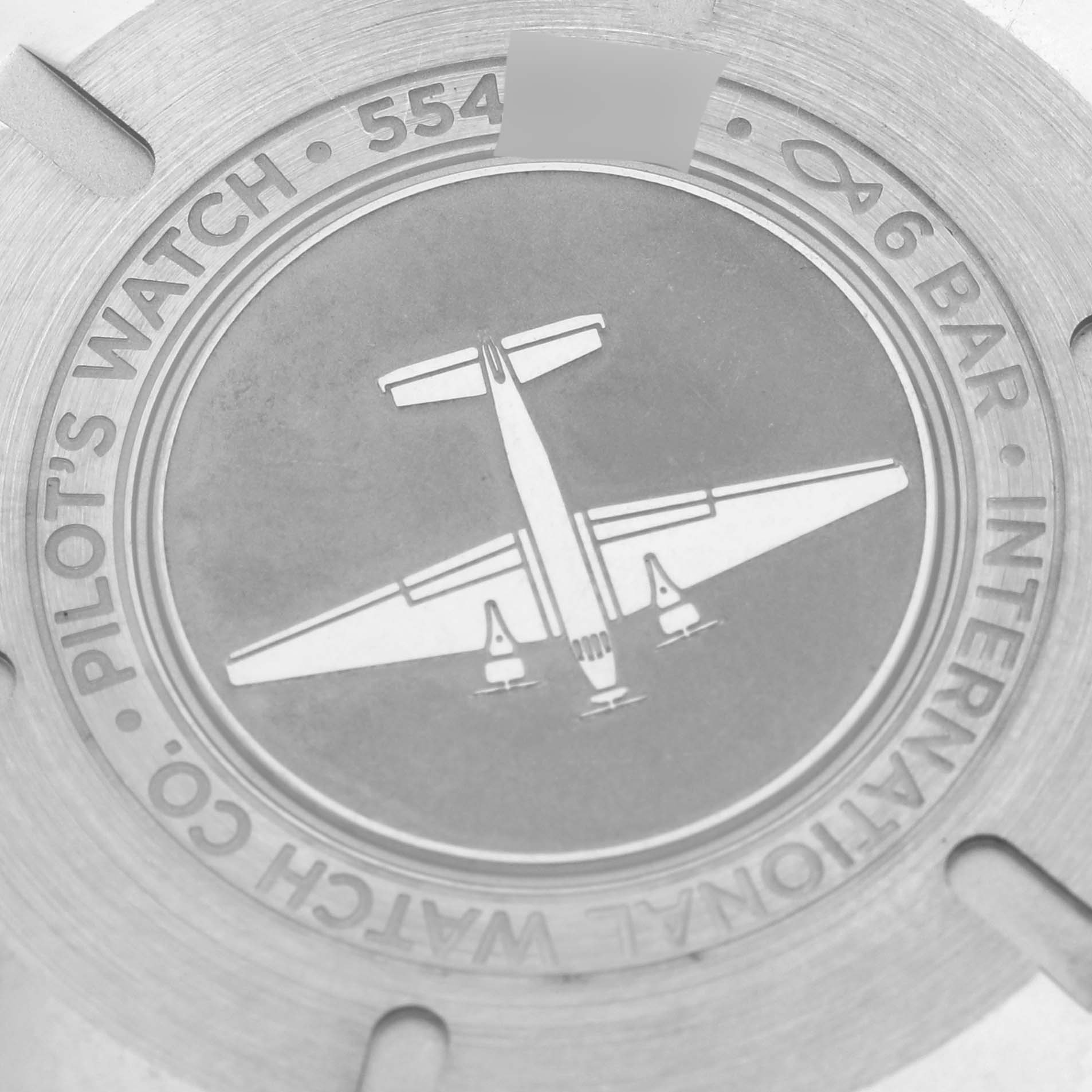 The image shows the engraved case back of the IWC Pilot IW327002 Men's Stainless Steel White Dial IW327002 Men's Stainless Steel White Dial model, featuring an airplane design and text detailing.
