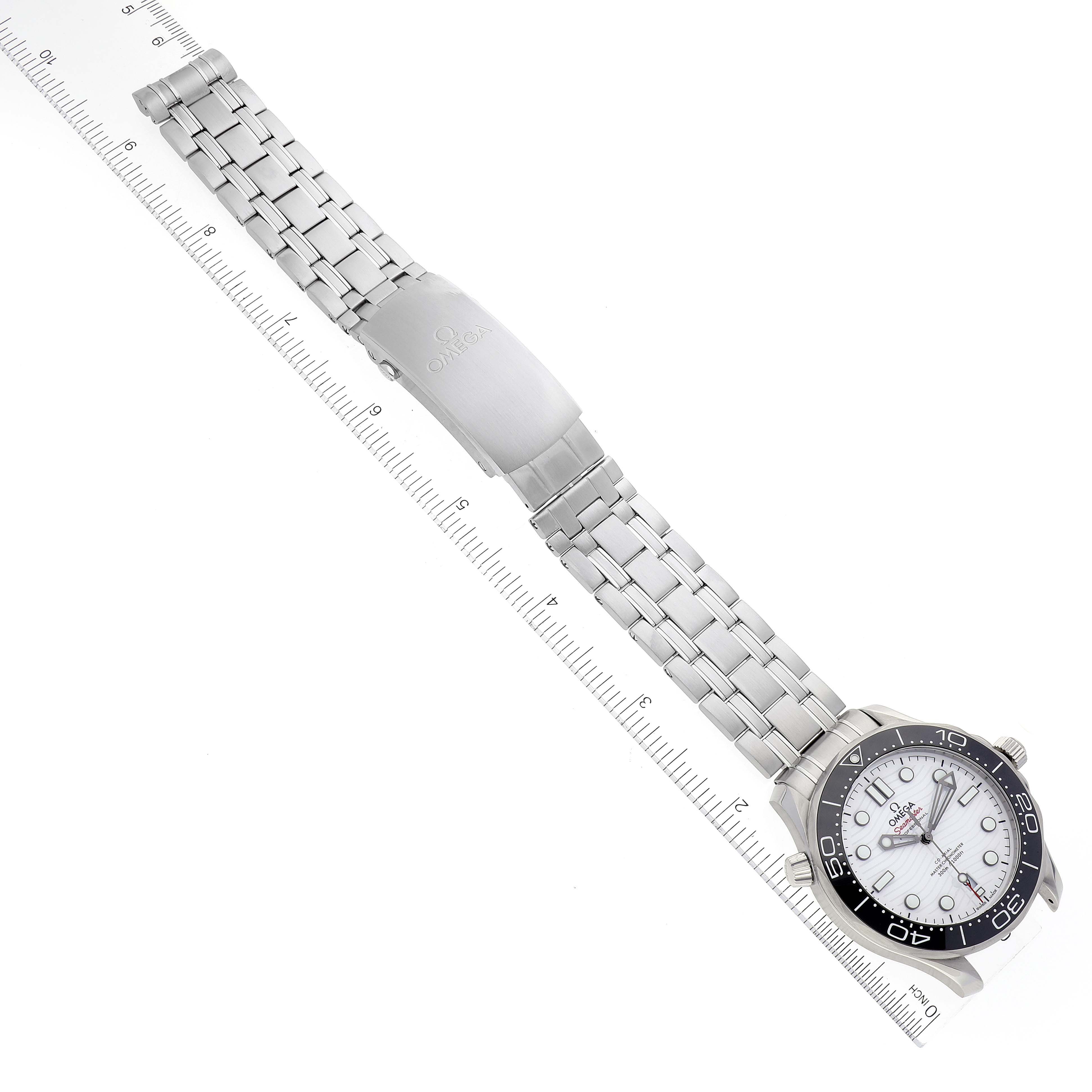 The image shows an Omega Seamaster 210.30.42.20.04.001 Men's Stainless Steel White Dial 210.30.42.20.04.001 Men's Stainless Steel White Dial watch from a top-down angle, featuring its metal bracelet and dial with a ruler alongside for scale.